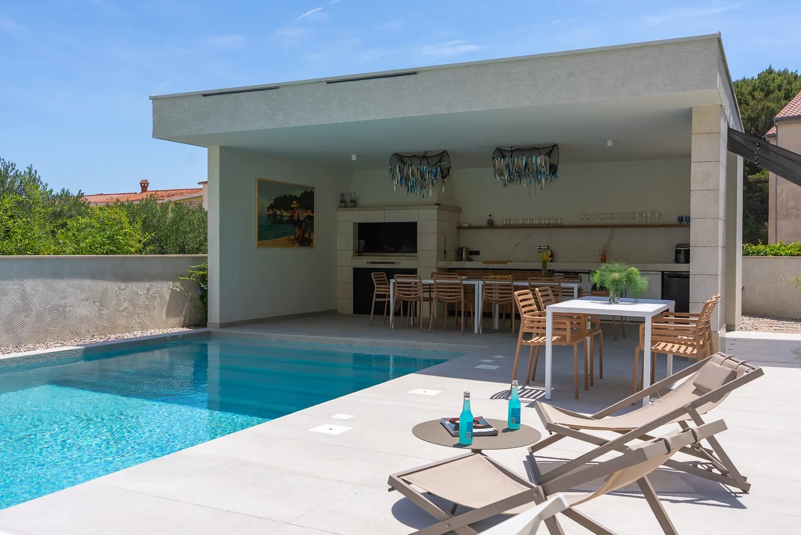 A swimming pool beside a covered outdoor dining area with a table and seating.