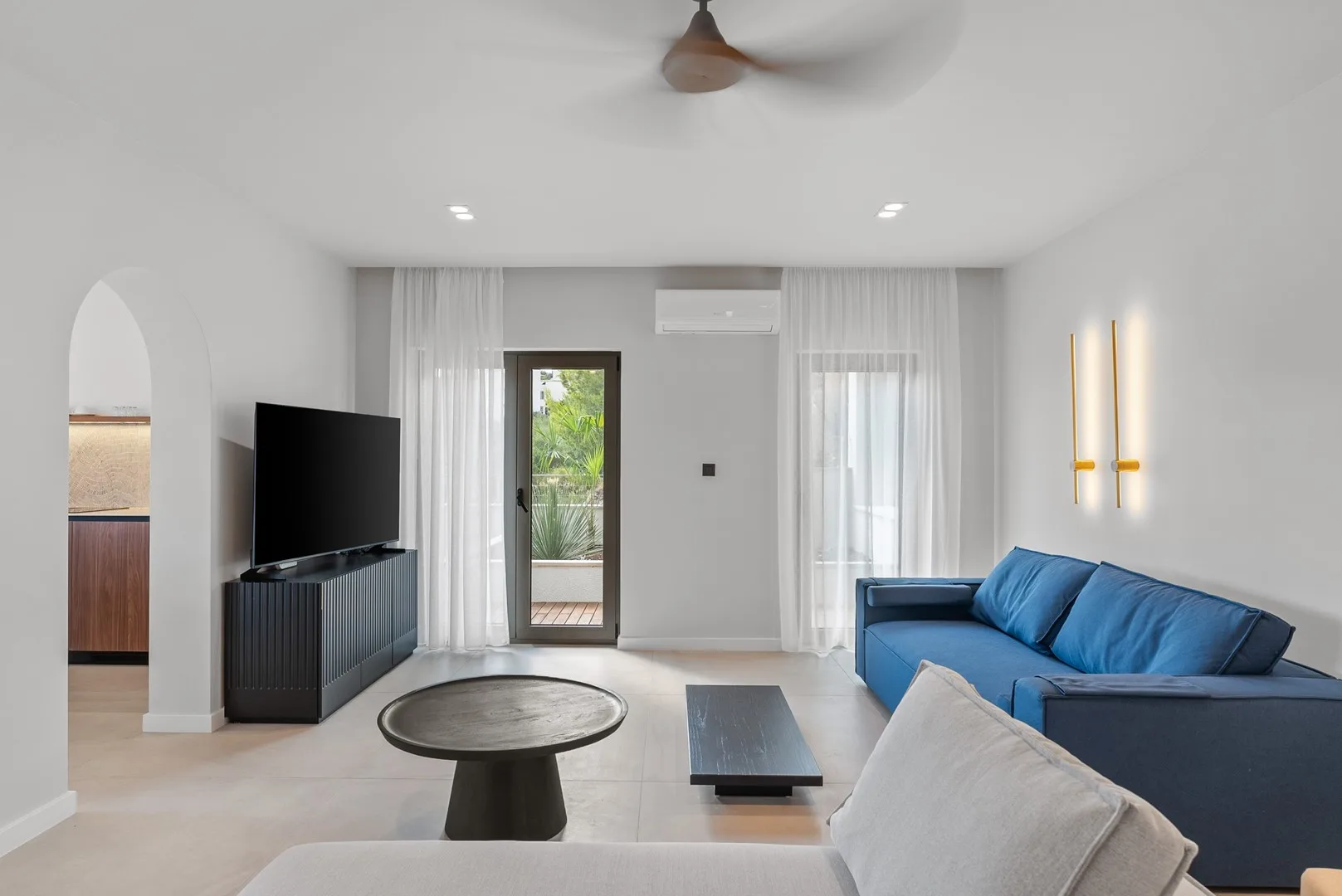 A bright living room with blue seating and a television.