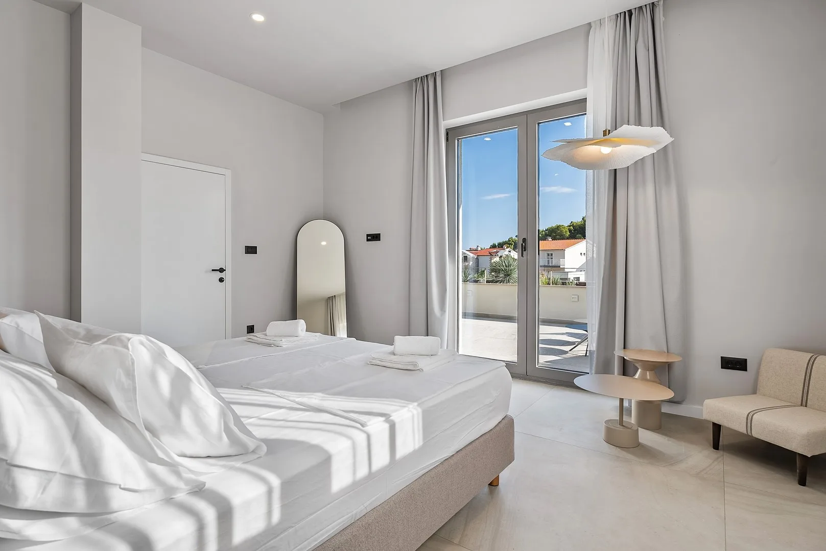 A bright bedroom with a bed and glass doors opening onto a balcony.