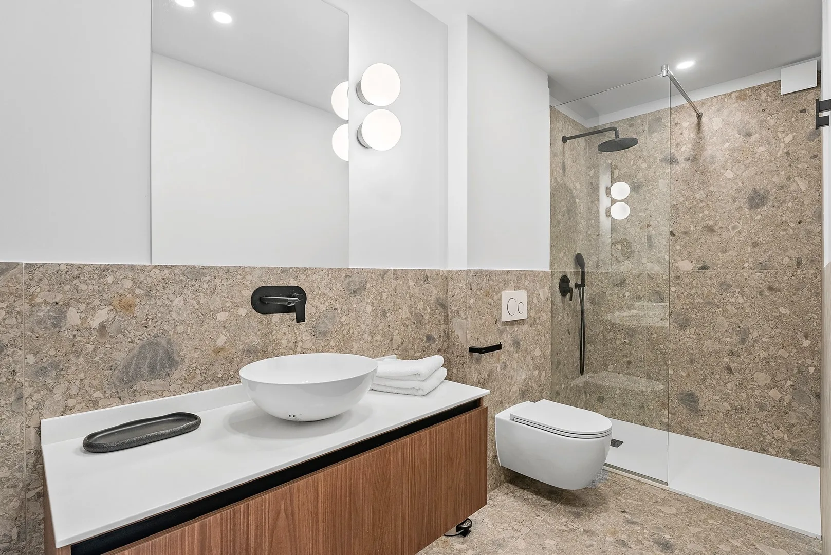A modern bathroom with a vessel sink and glass-enclosed shower.