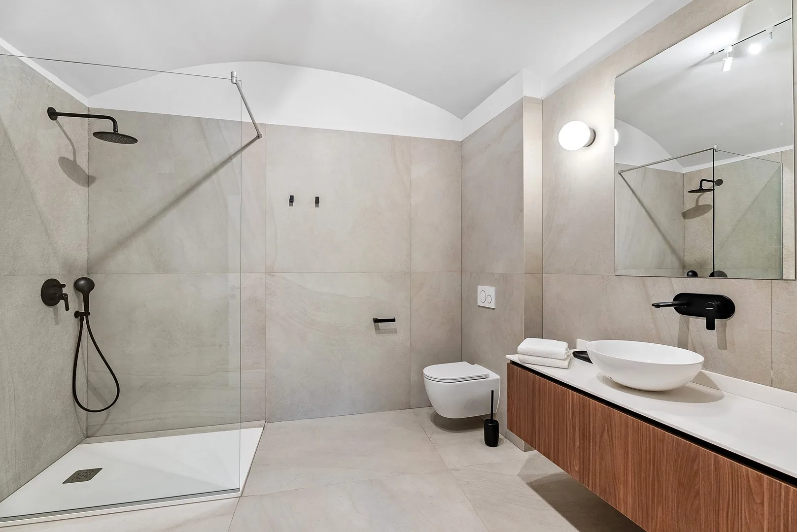 A modern bathroom with a walk-in shower and a vanity topped by a vessel sink.