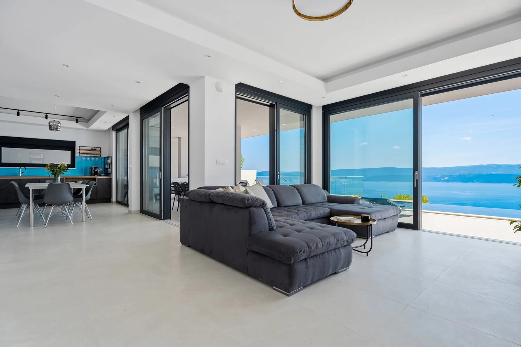 A bright living room with seating beside wide windows overlooking the sea.