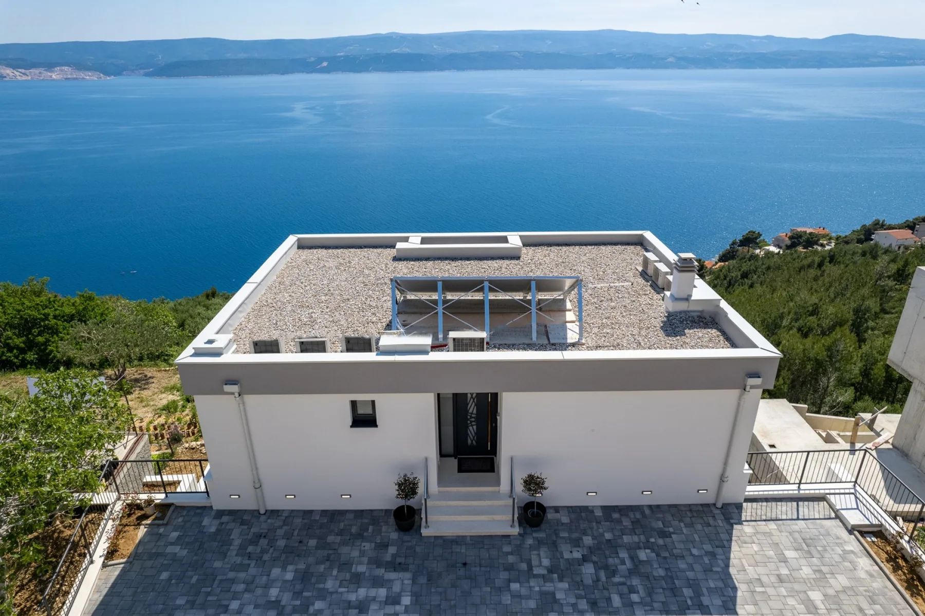 A modern house with a flat rooftop terrace overlooking the sea.