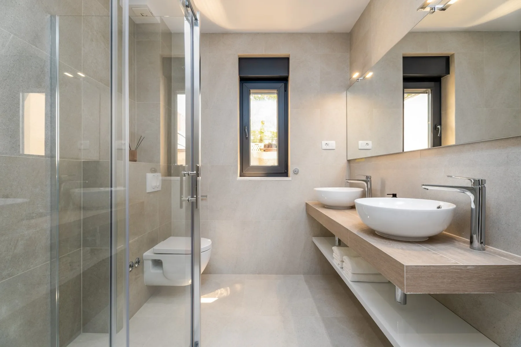 A modern bathroom with a glass shower and a long vanity.