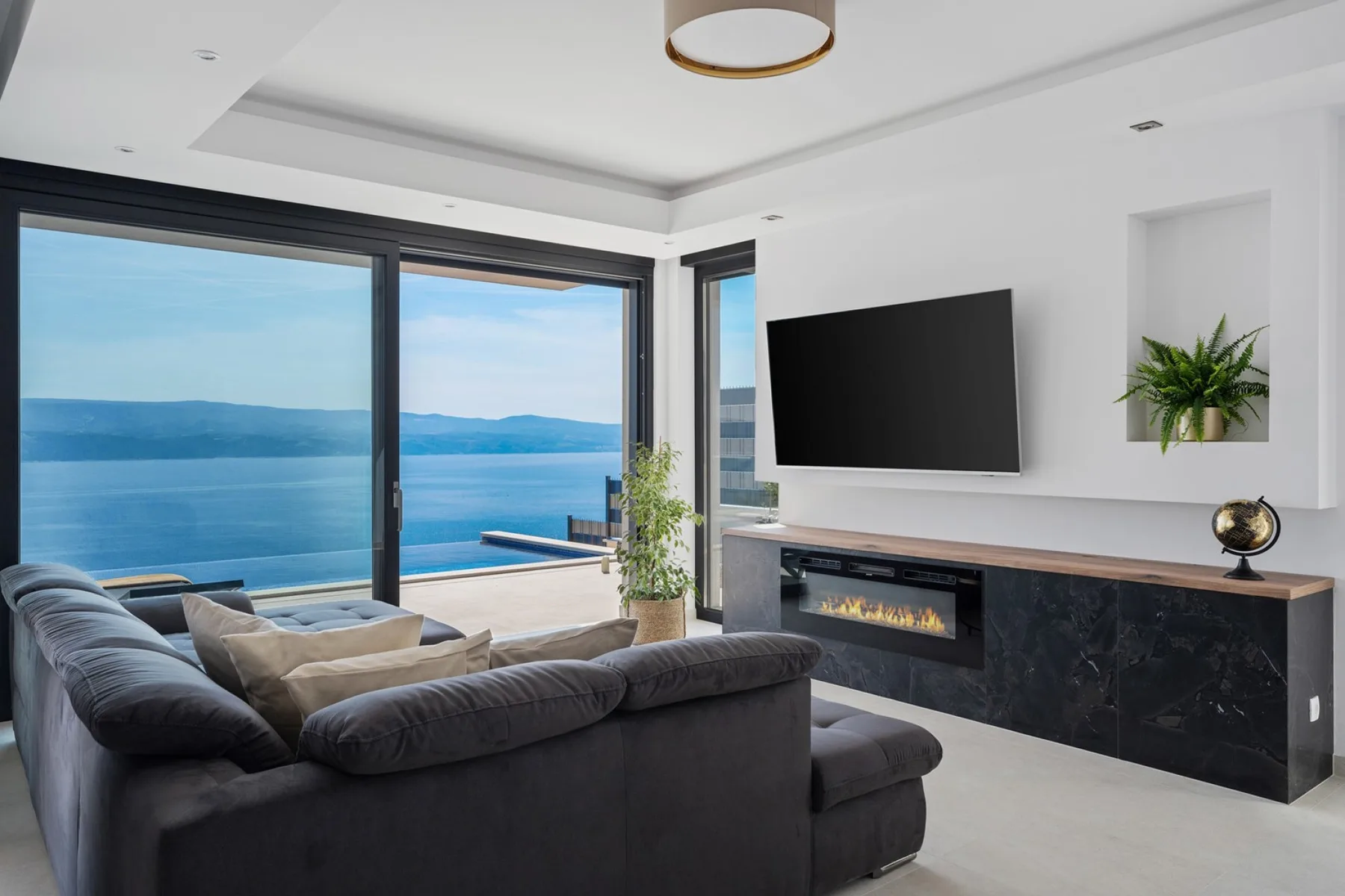 A living room with seating facing a television and a wide view of the water.