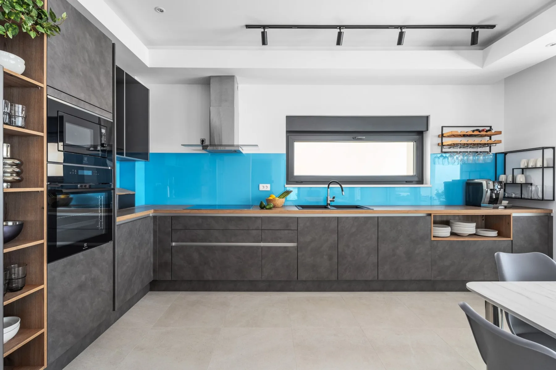 A modern kitchen with dark cabinetry and a bright blue backsplash.