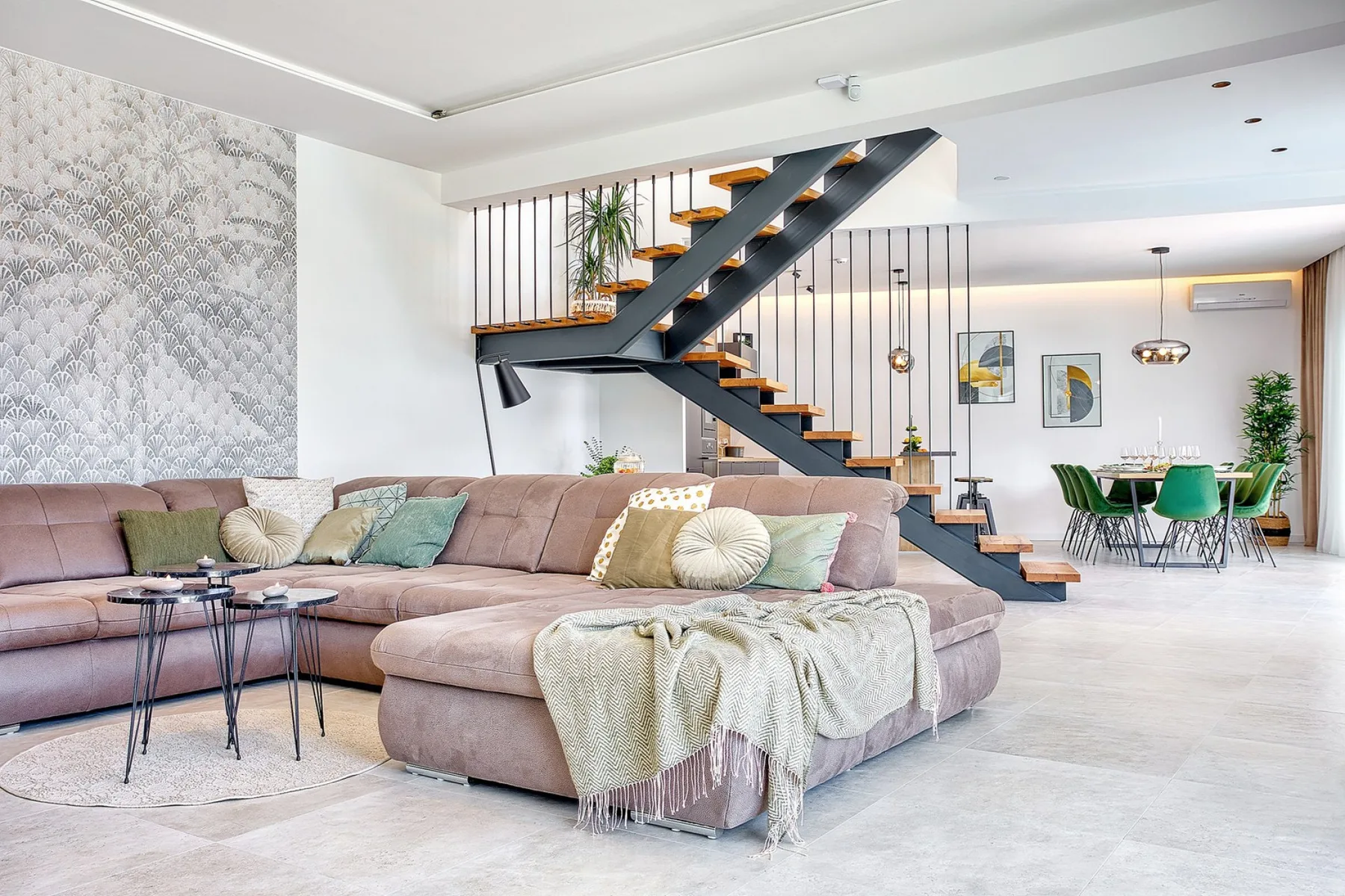 An open-plan living and dining area features a sectional seating area and a staircase.