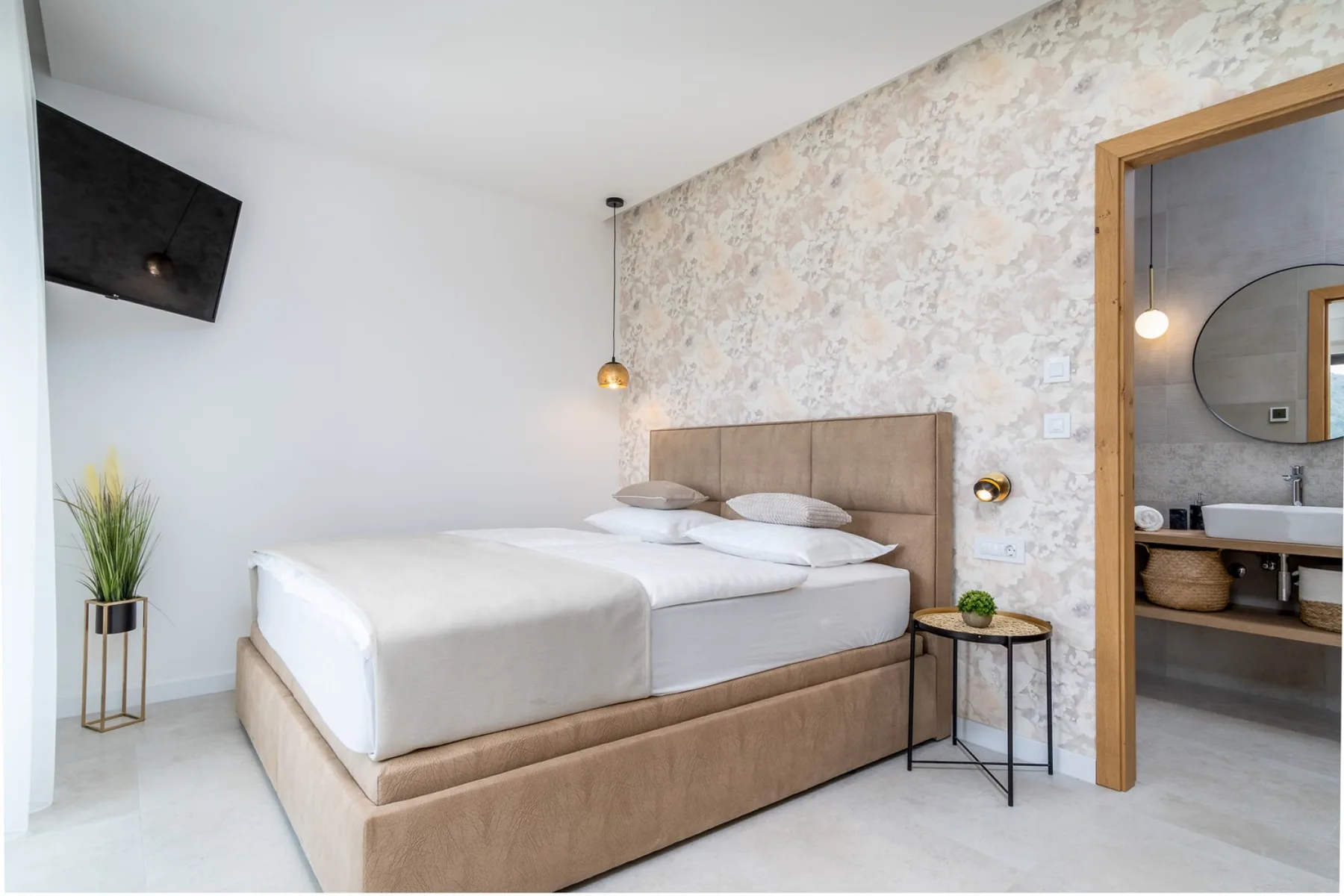 A bedroom with a large bed beside a small round side table.