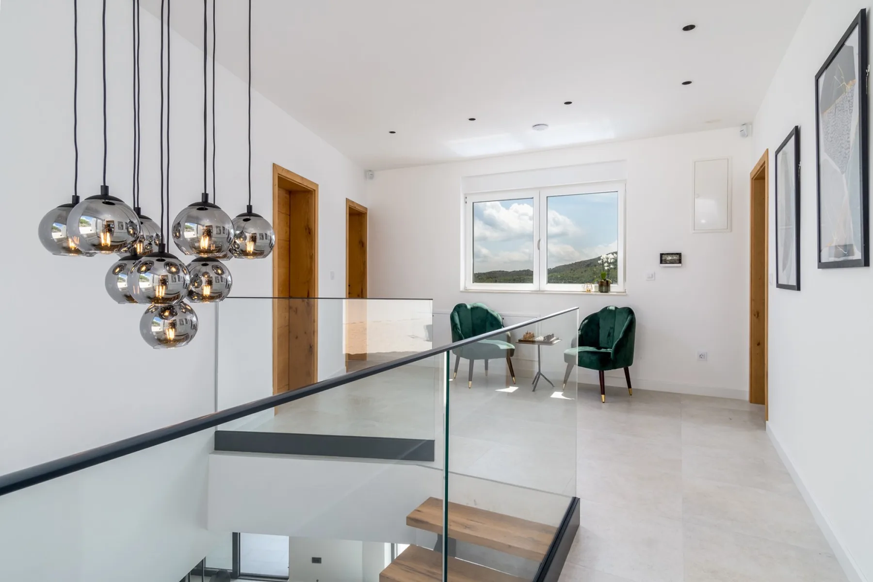 A bright interior landing overlooks a glass railing and a seating area by the window.