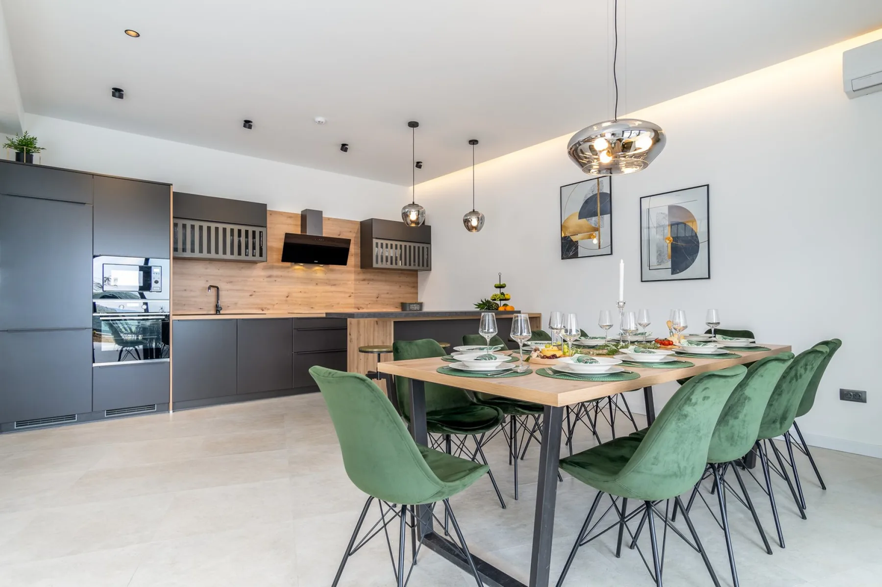 A modern kitchen and dining area with a set table and green seating.