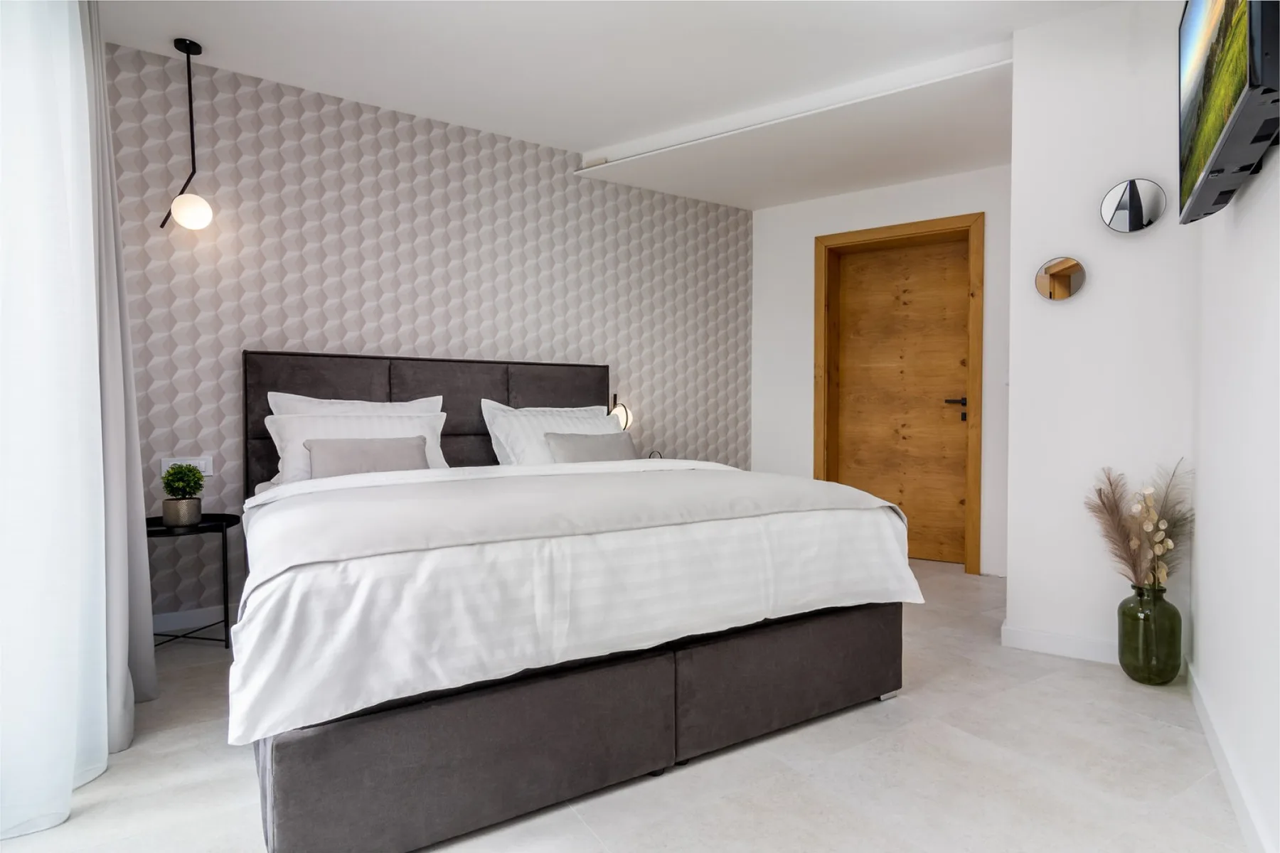 A bedroom with a neatly made bed and a wooden door.