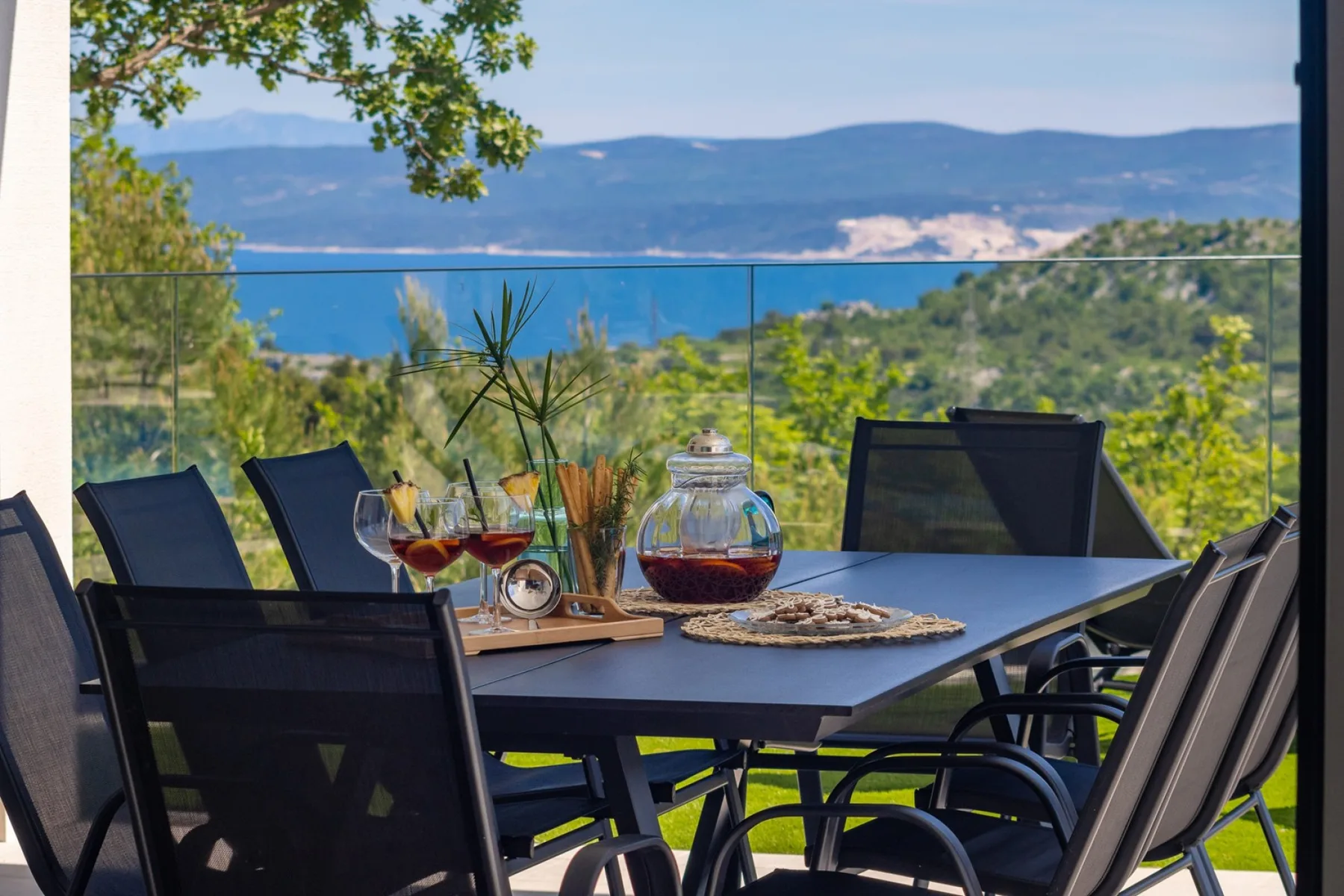 Outdoor dining area with a table and seating overlooking a wooded landscape.