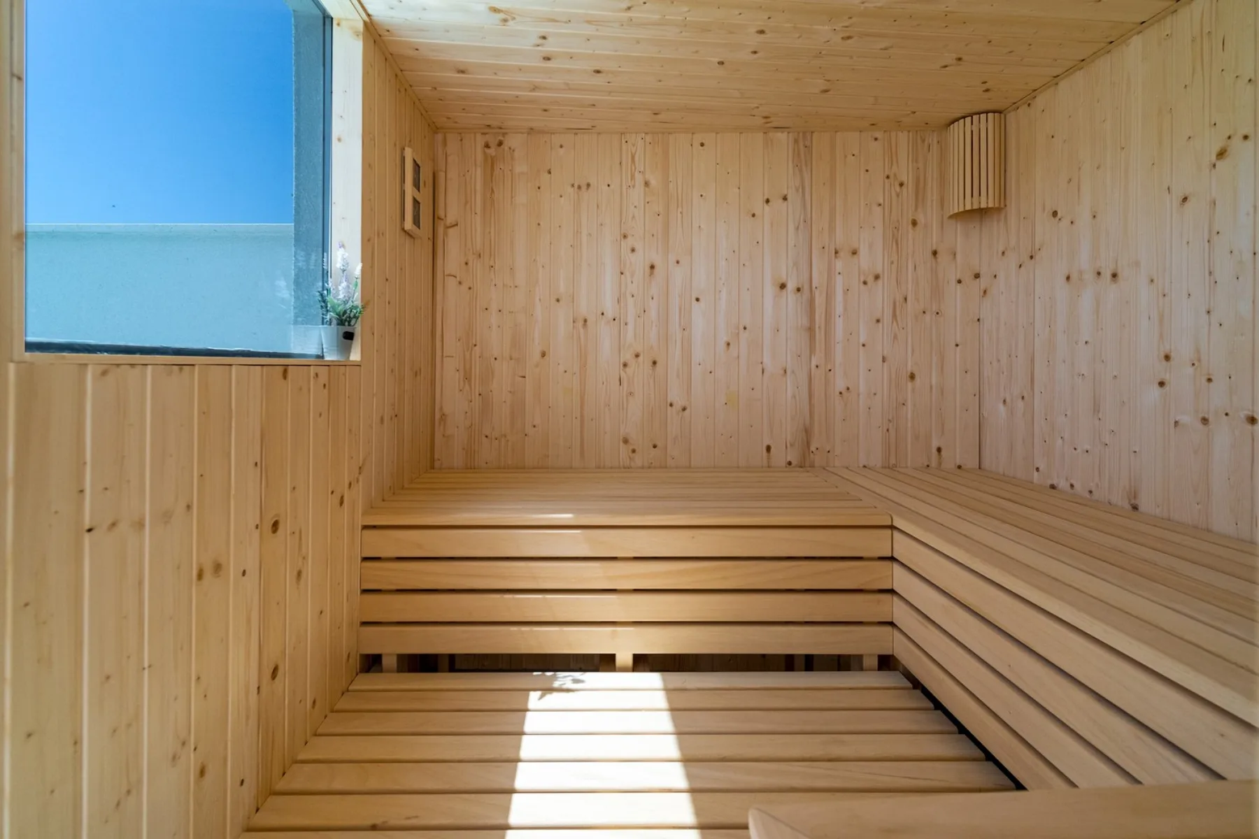 A wooden sauna room with tiered seating and a window.