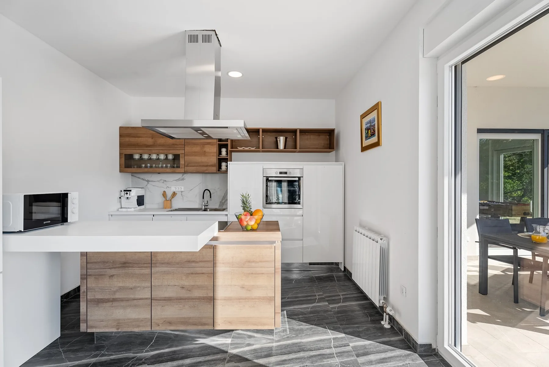 A modern kitchen with wooden cabinets and a central island topped with fruit.