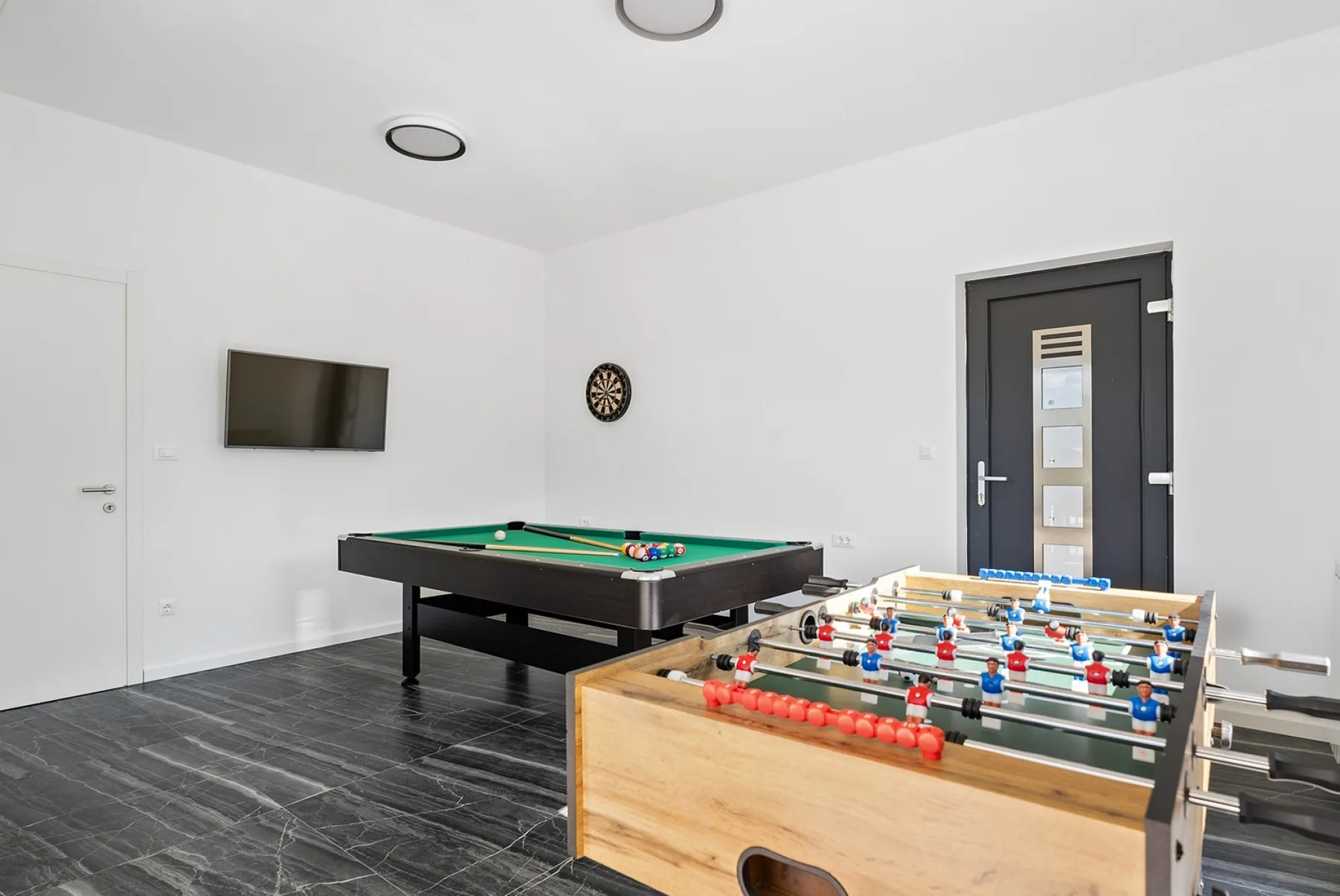 A recreation room with a foosball table and a pool table.