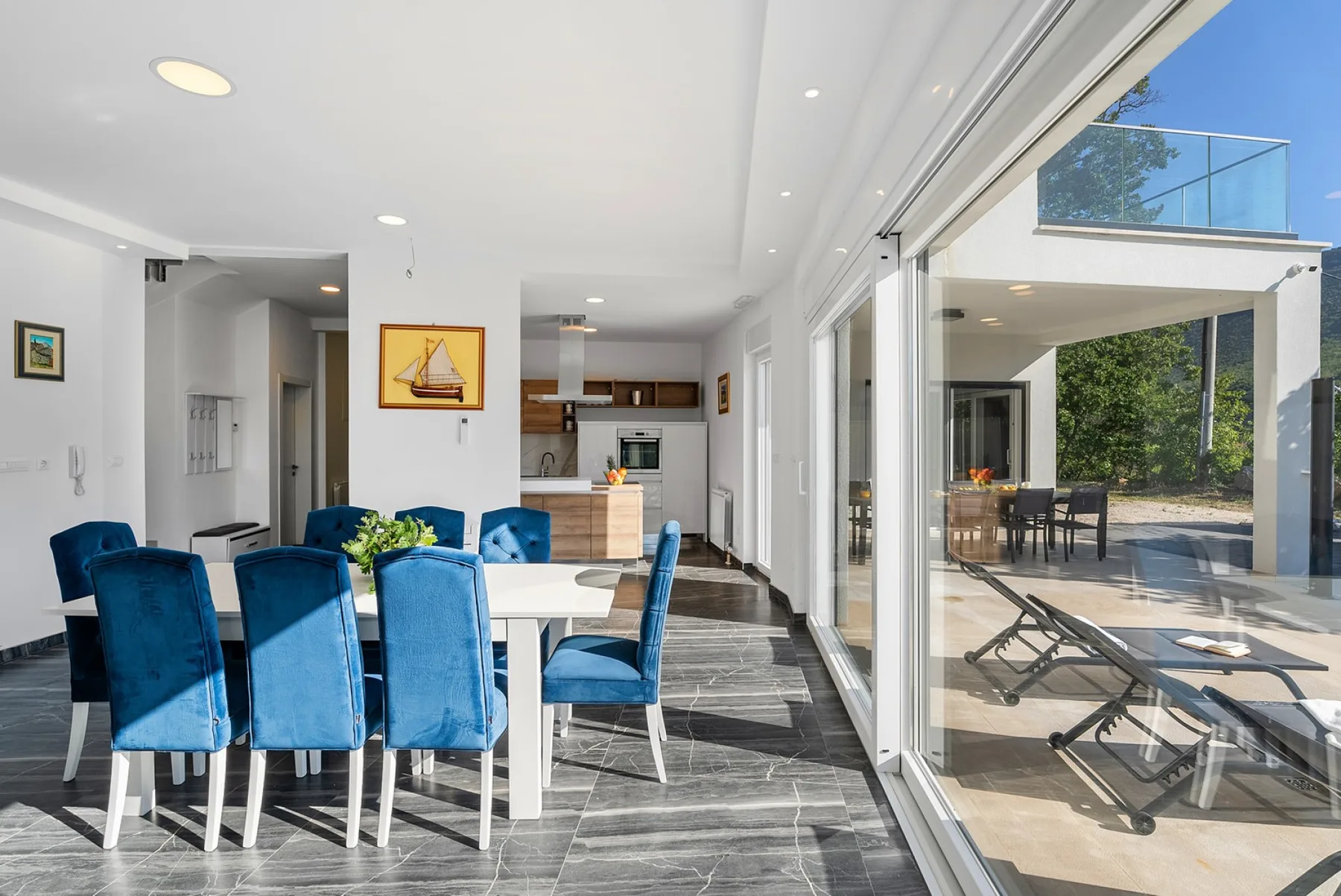 A bright dining area with blue seating opens onto a patio.