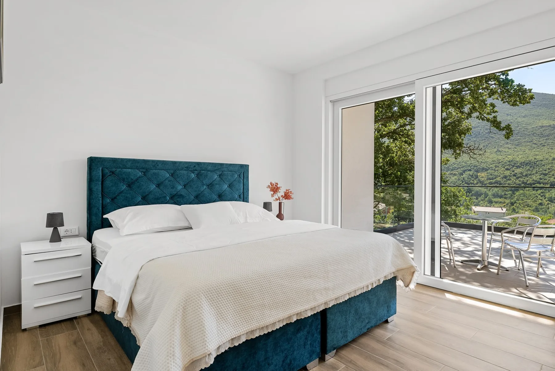 A bedroom with a neatly made bed beside large sliding glass doors.