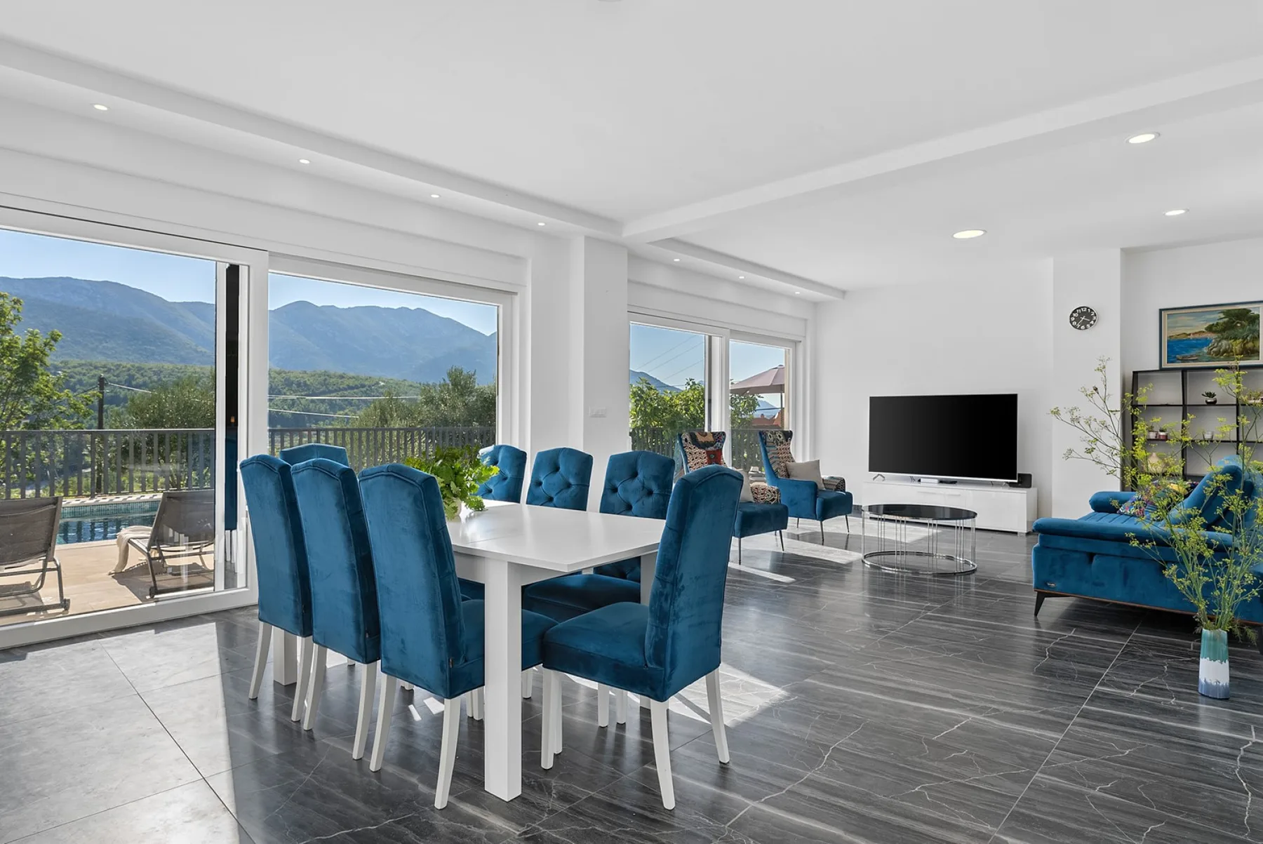 A bright living and dining area opens onto a balcony with mountain views.