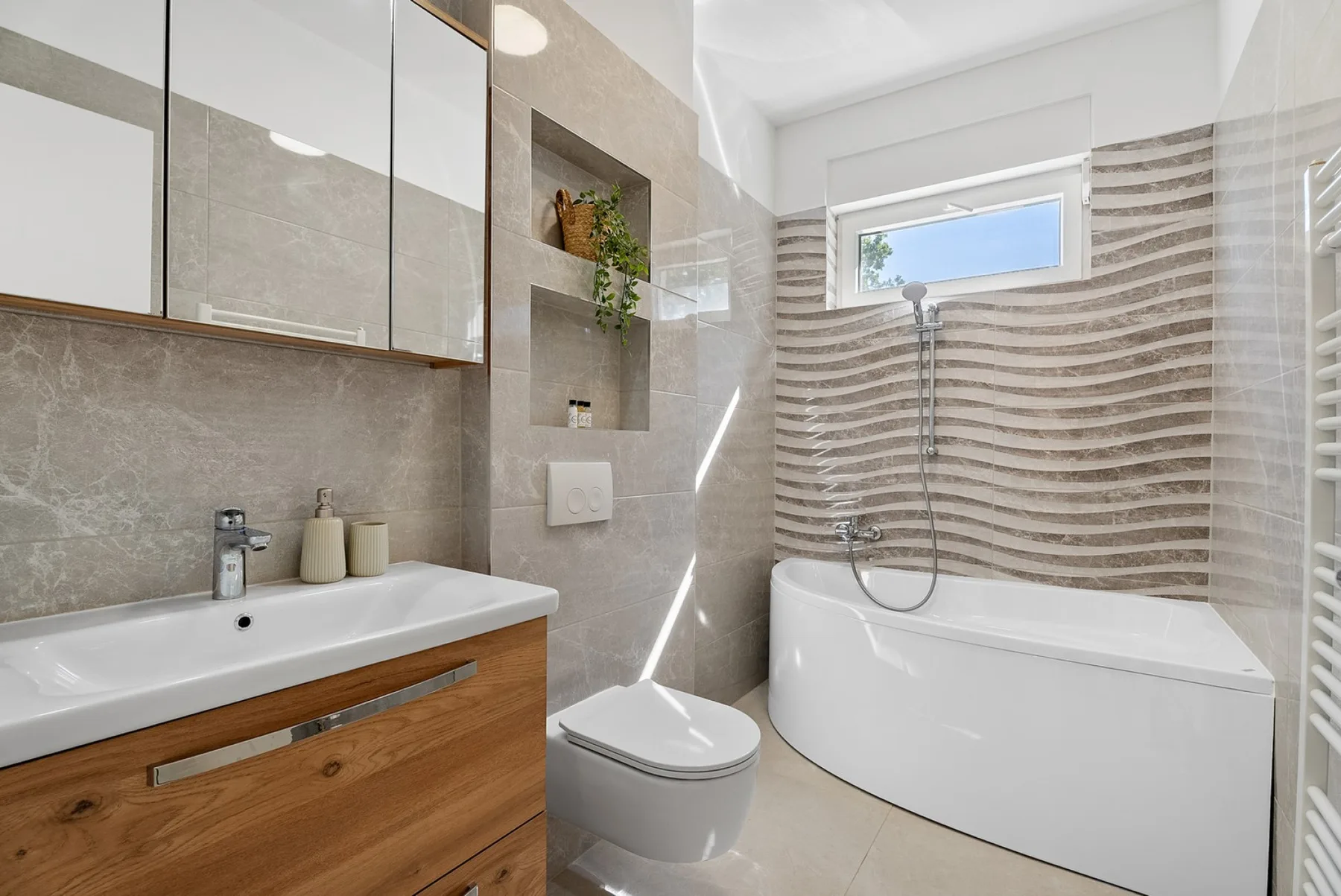 A modern bathroom with a bathtub, sink, and wood-front vanity.