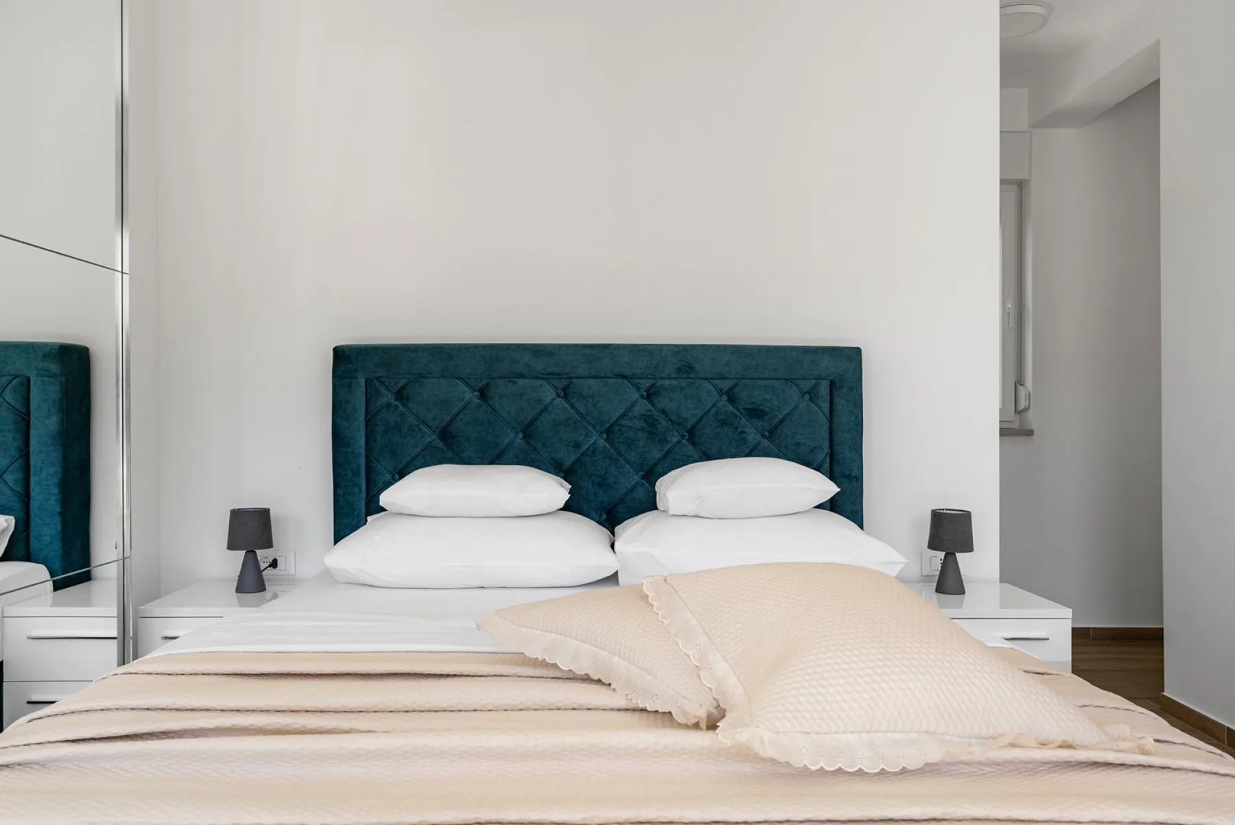A bedroom with a bed, white bedding, and a teal upholstered headboard.