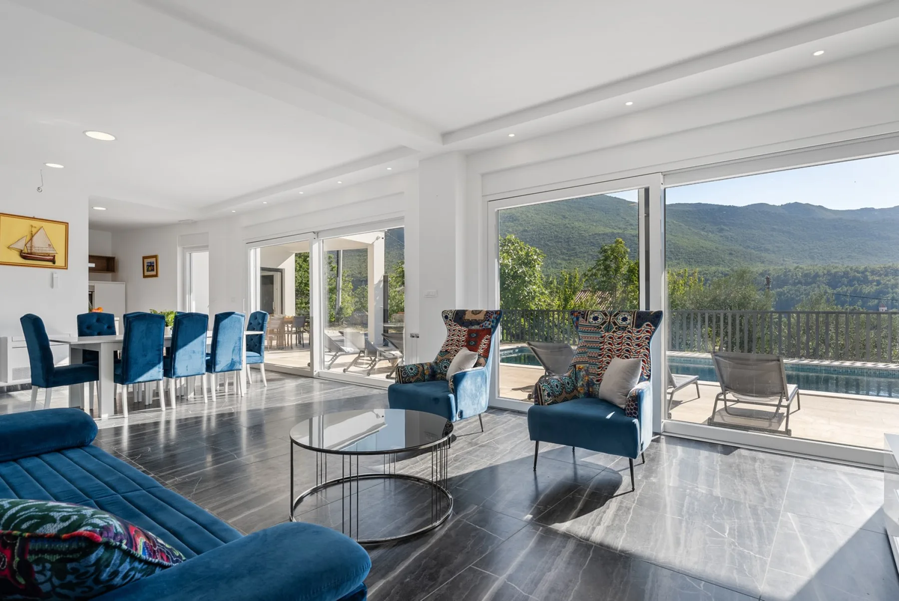A bright open living and dining area with seating beside large windows.