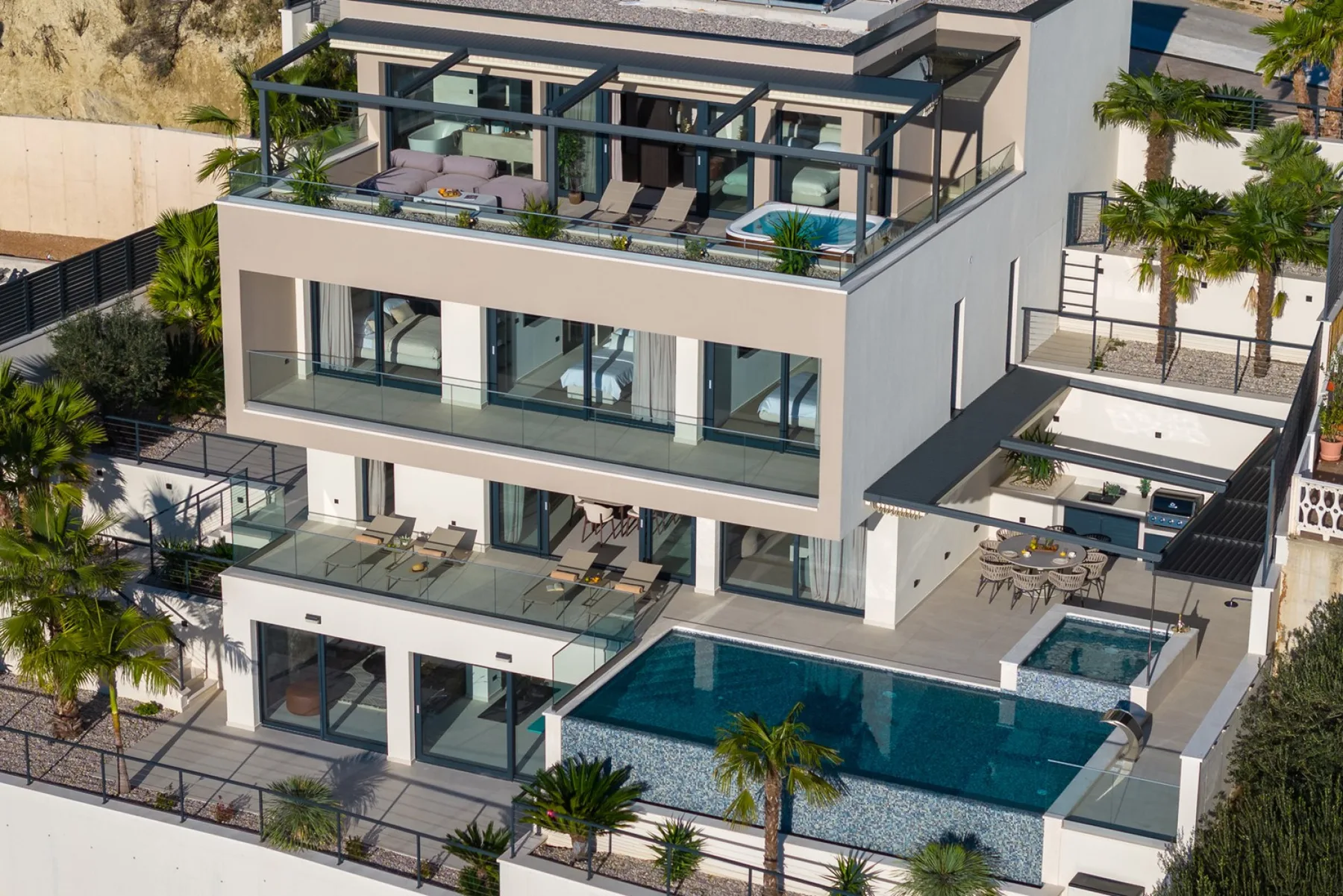 A modern multi-level house with glass balconies and a swimming pool.