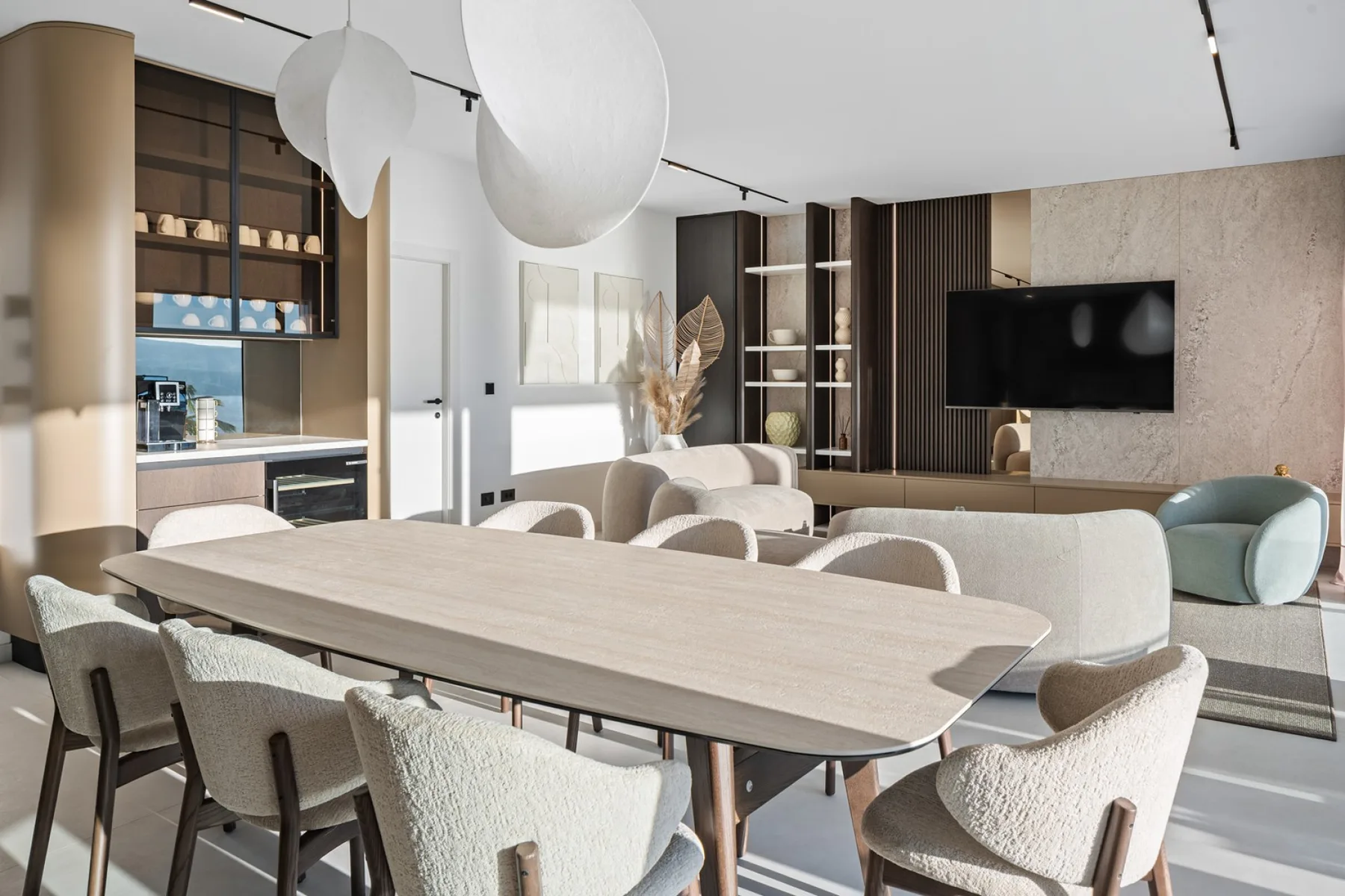 A modern living and dining area with a long table and seating around it.