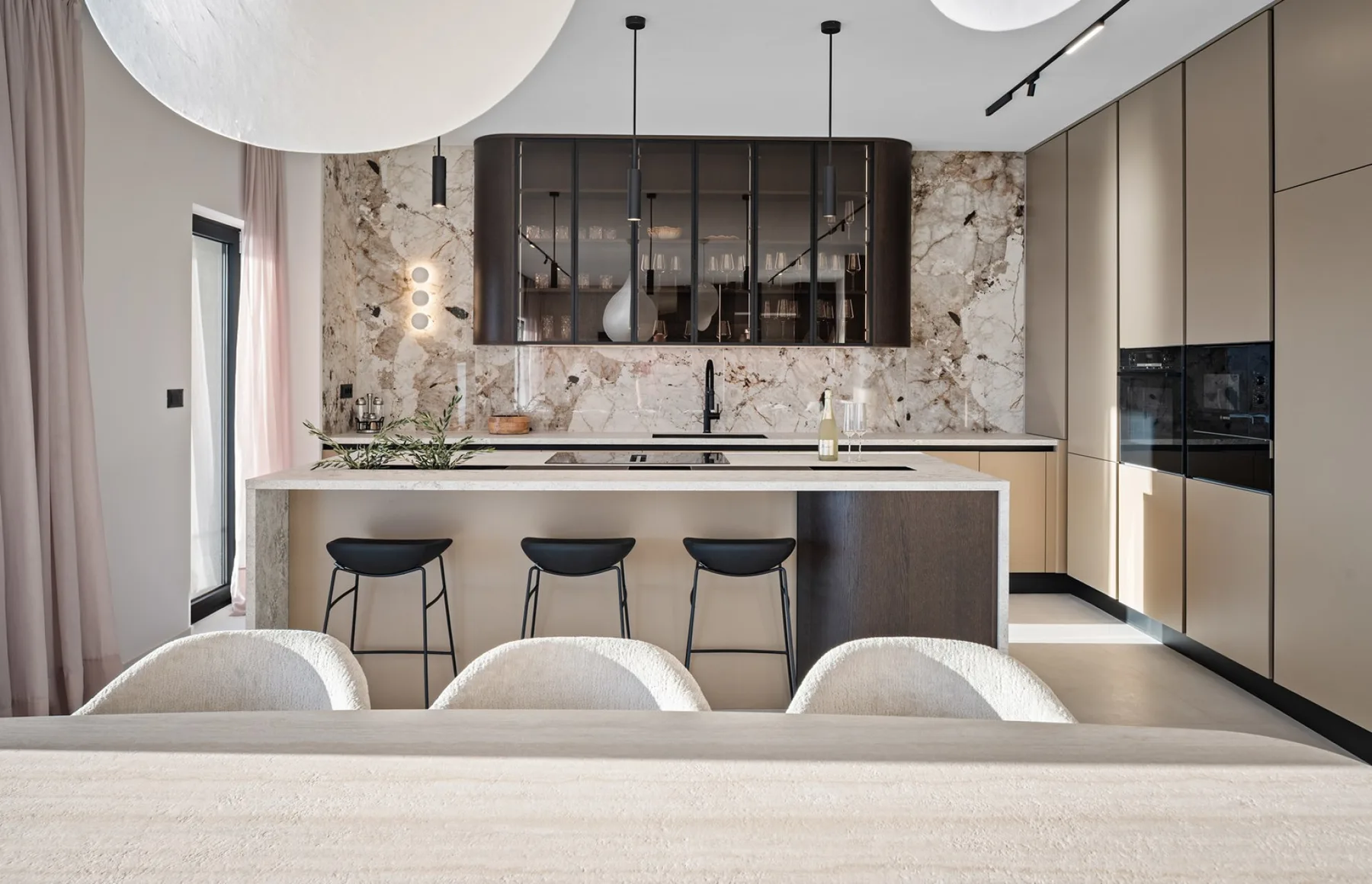 A modern kitchen with a central island, bar seating, and a marble-patterned backsplash.
