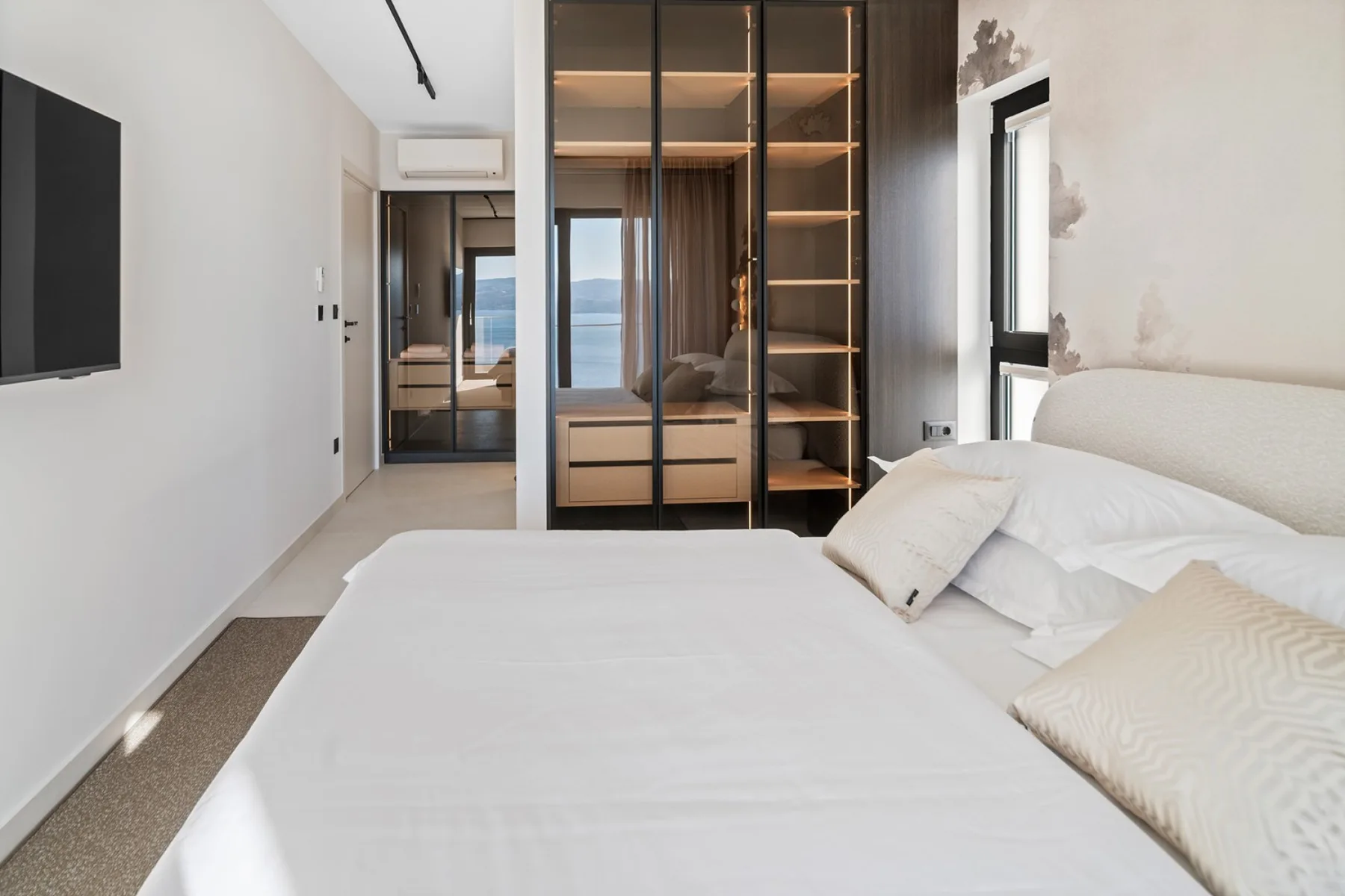 A bright bedroom with a large bed and a mirrored wardrobe.