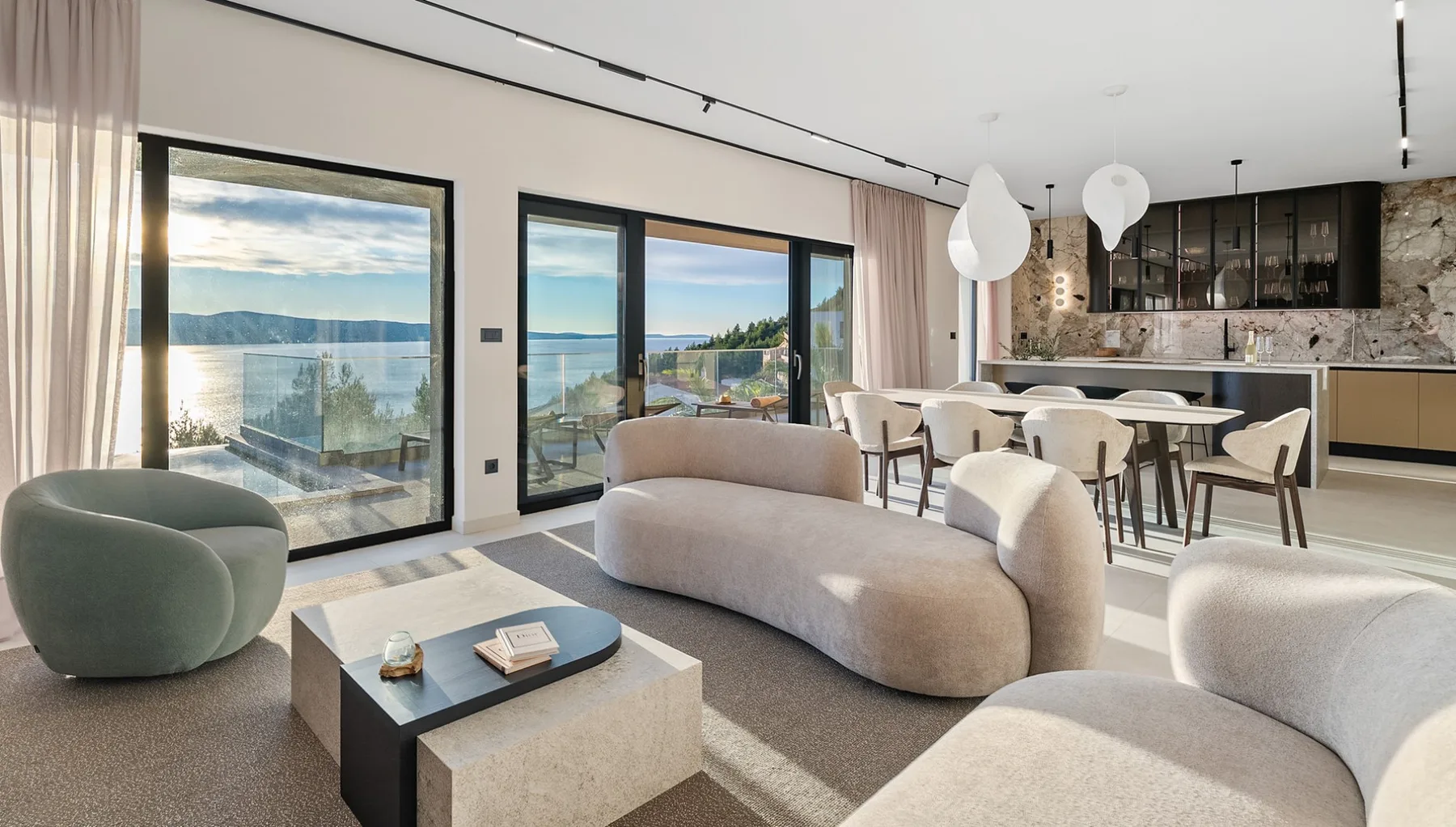 A modern living and dining area with large windows overlooking the water.