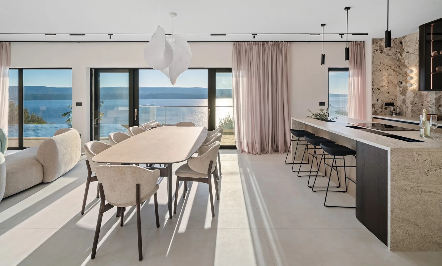 An open-plan dining area and kitchen overlook the water through large windows.