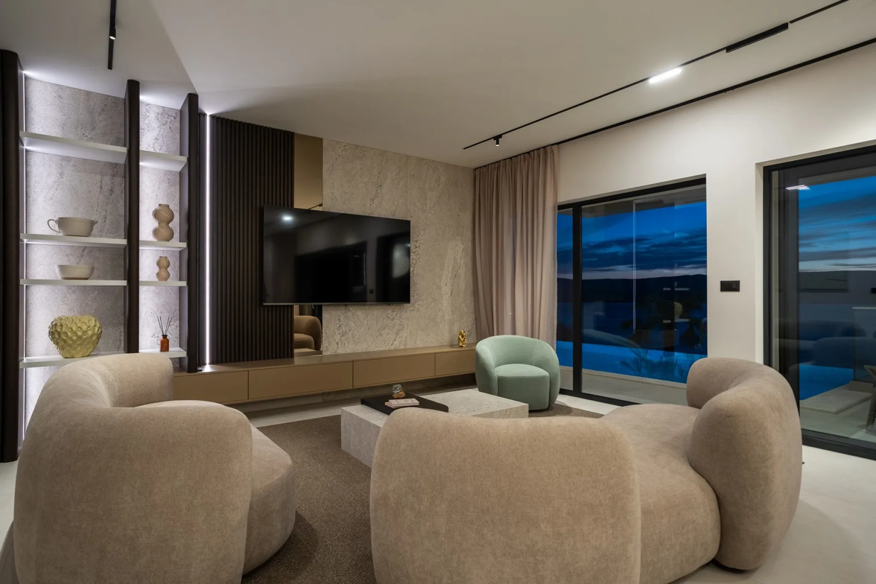 A modern living room with curved seating, a television, and large windows.