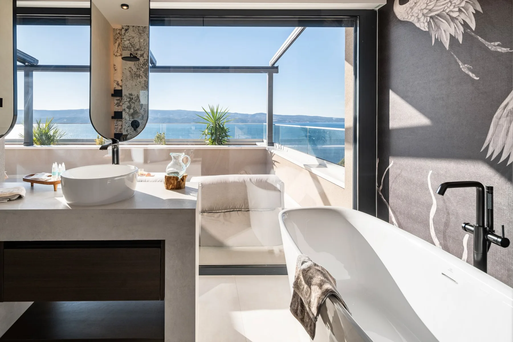 A bright bathroom with a bathtub and a wide view of the water.