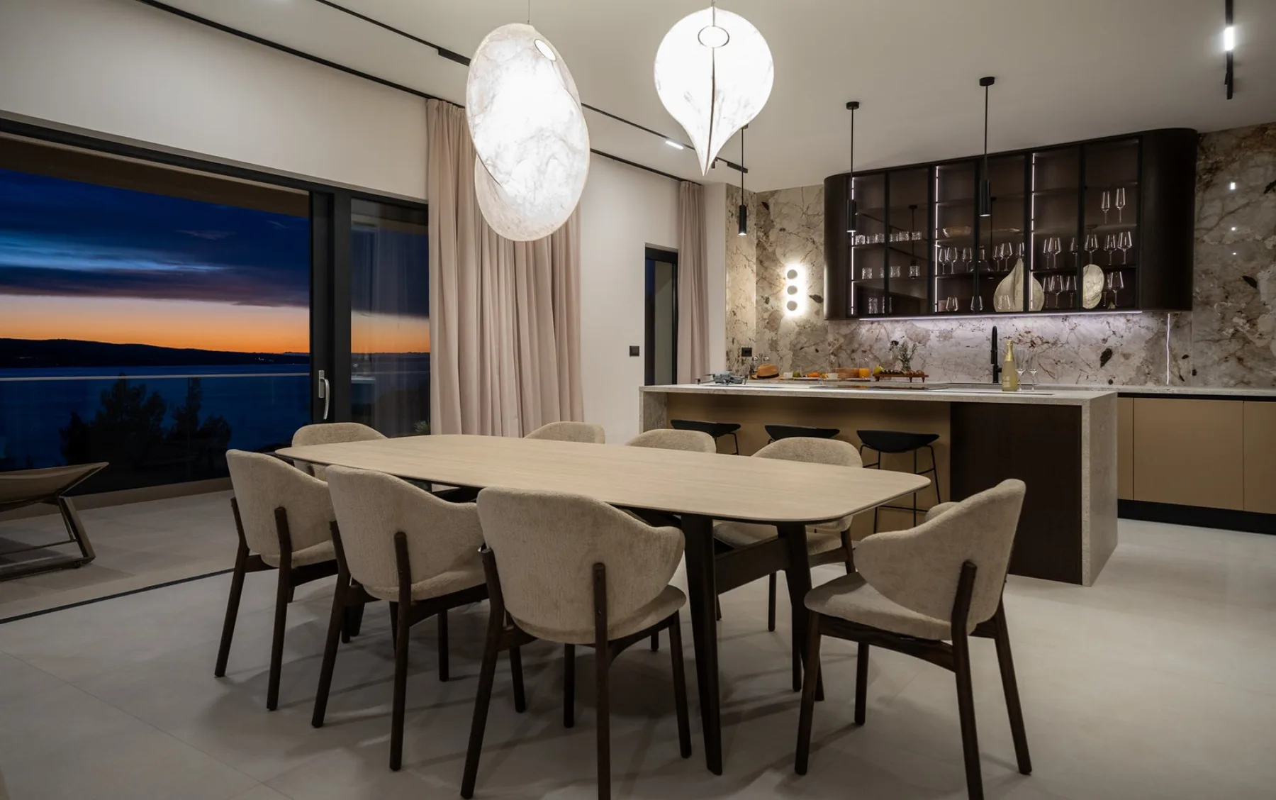 A dining area with a long table and seating beside an open kitchen.