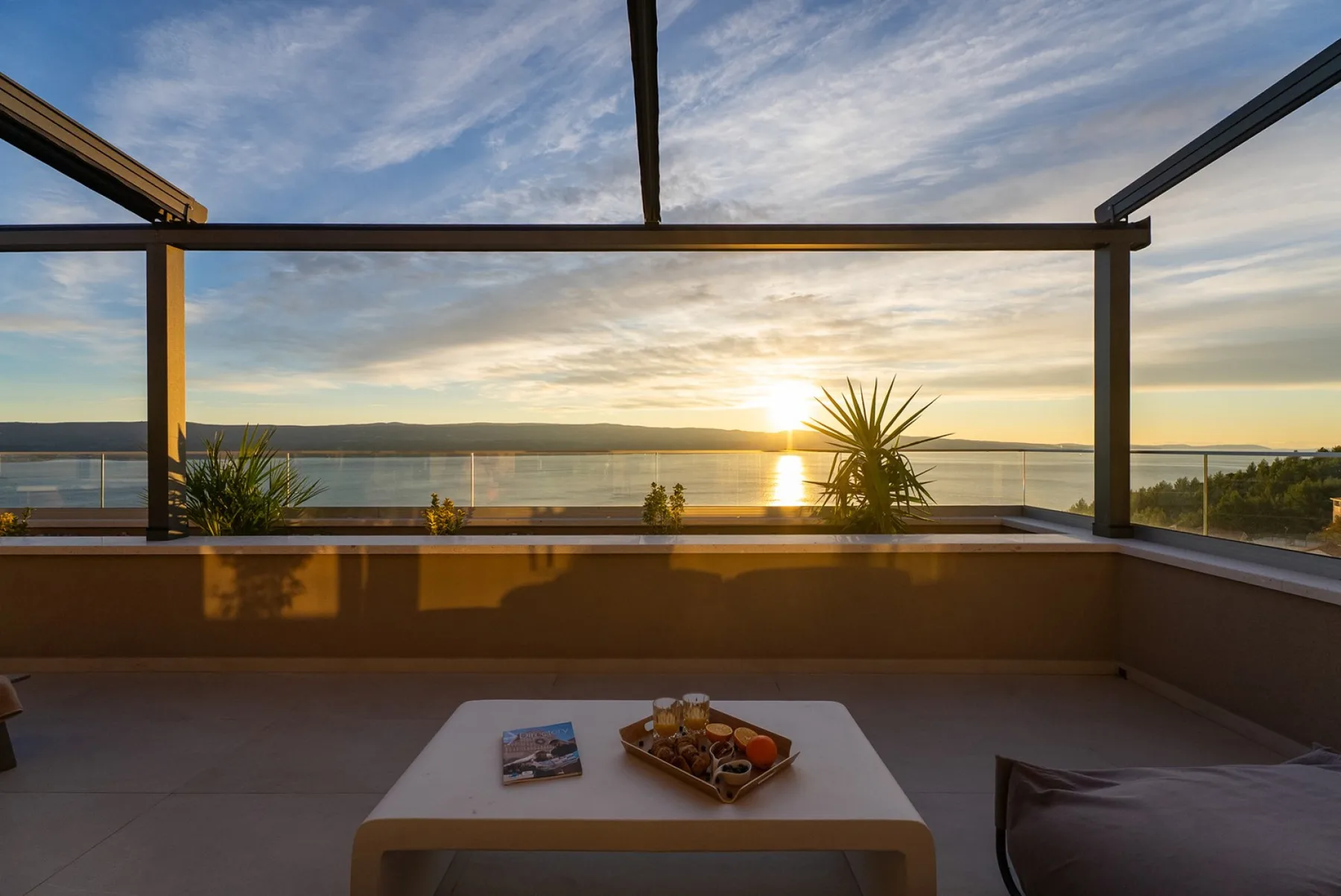 A terrace seating area overlooks the water at sunset.