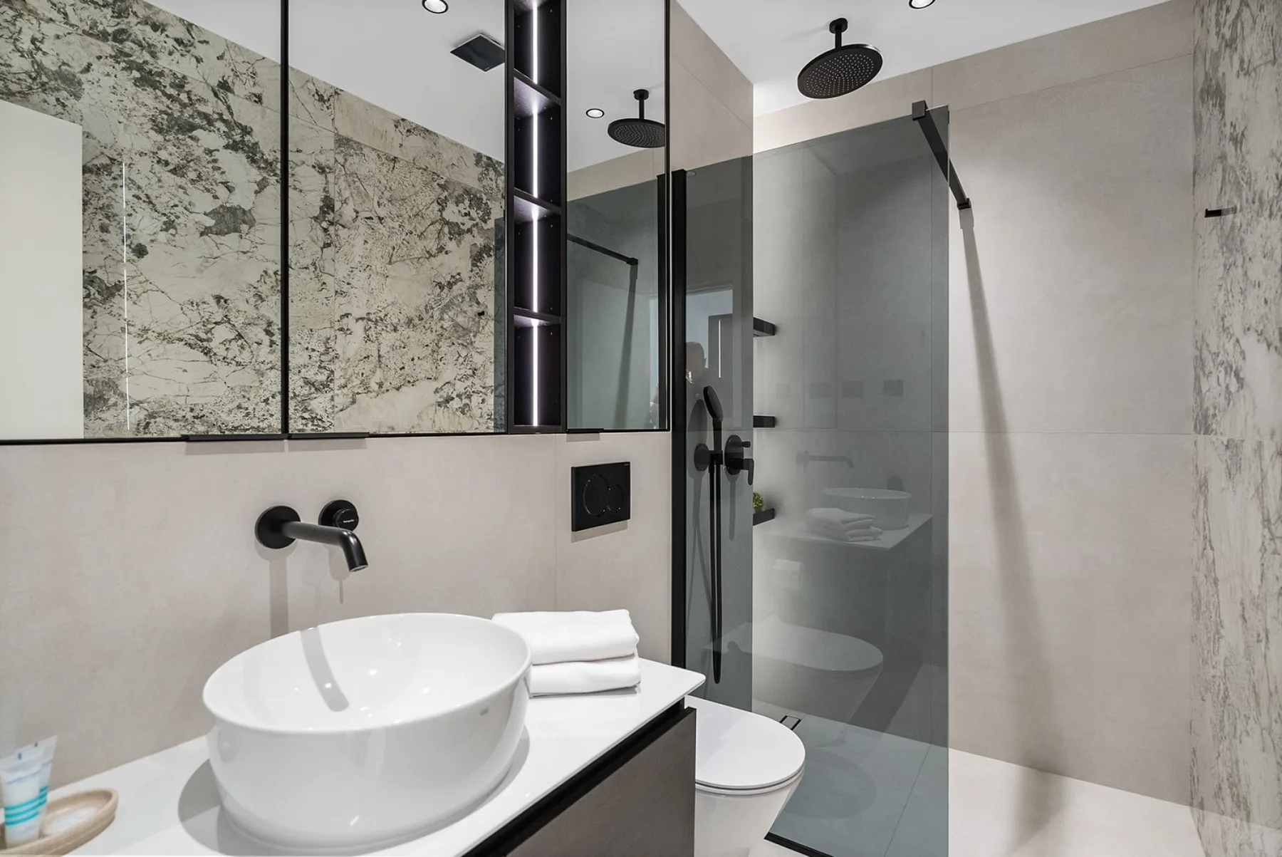 A modern bathroom with a white basin, toilet, and glass shower.