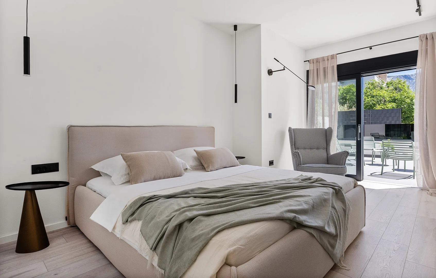A bright bedroom with a large bed and glass doors opening onto a patio.