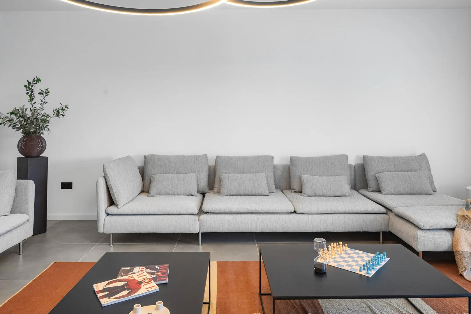 A modern living room with a large sectional seating area and low coffee tables.