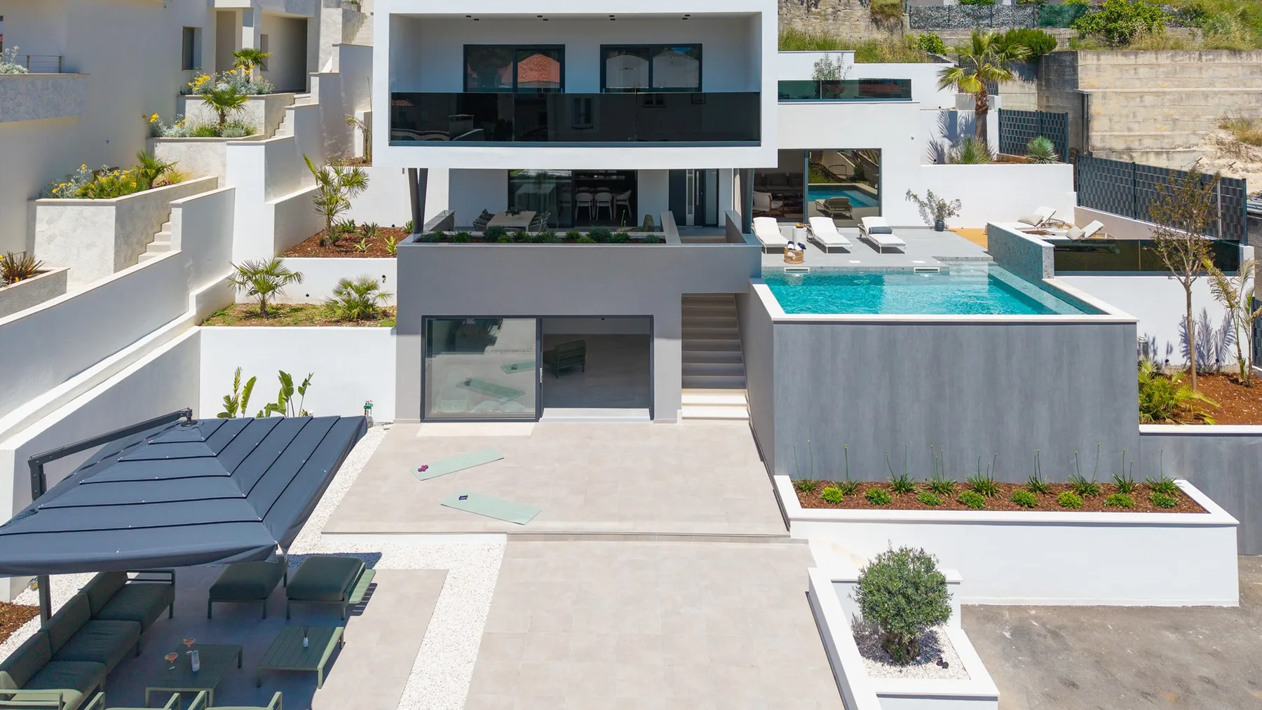 Modern house courtyard with a swimming pool and shaded outdoor seating.