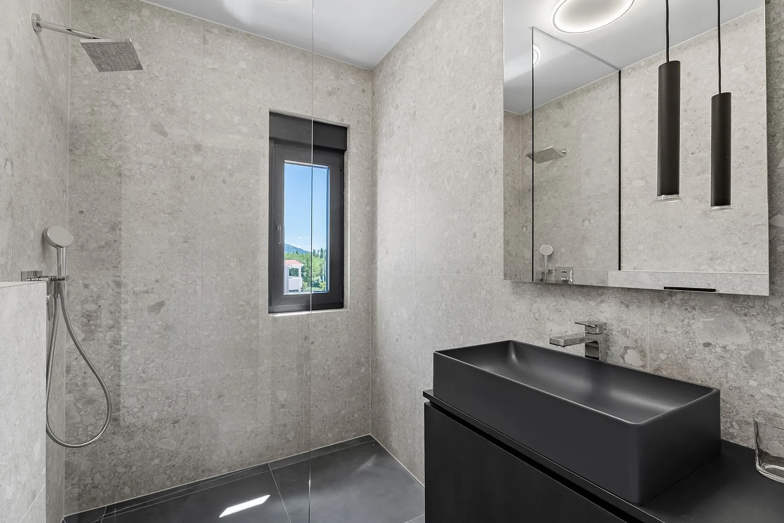 A modern bathroom with a dark sink and a window.