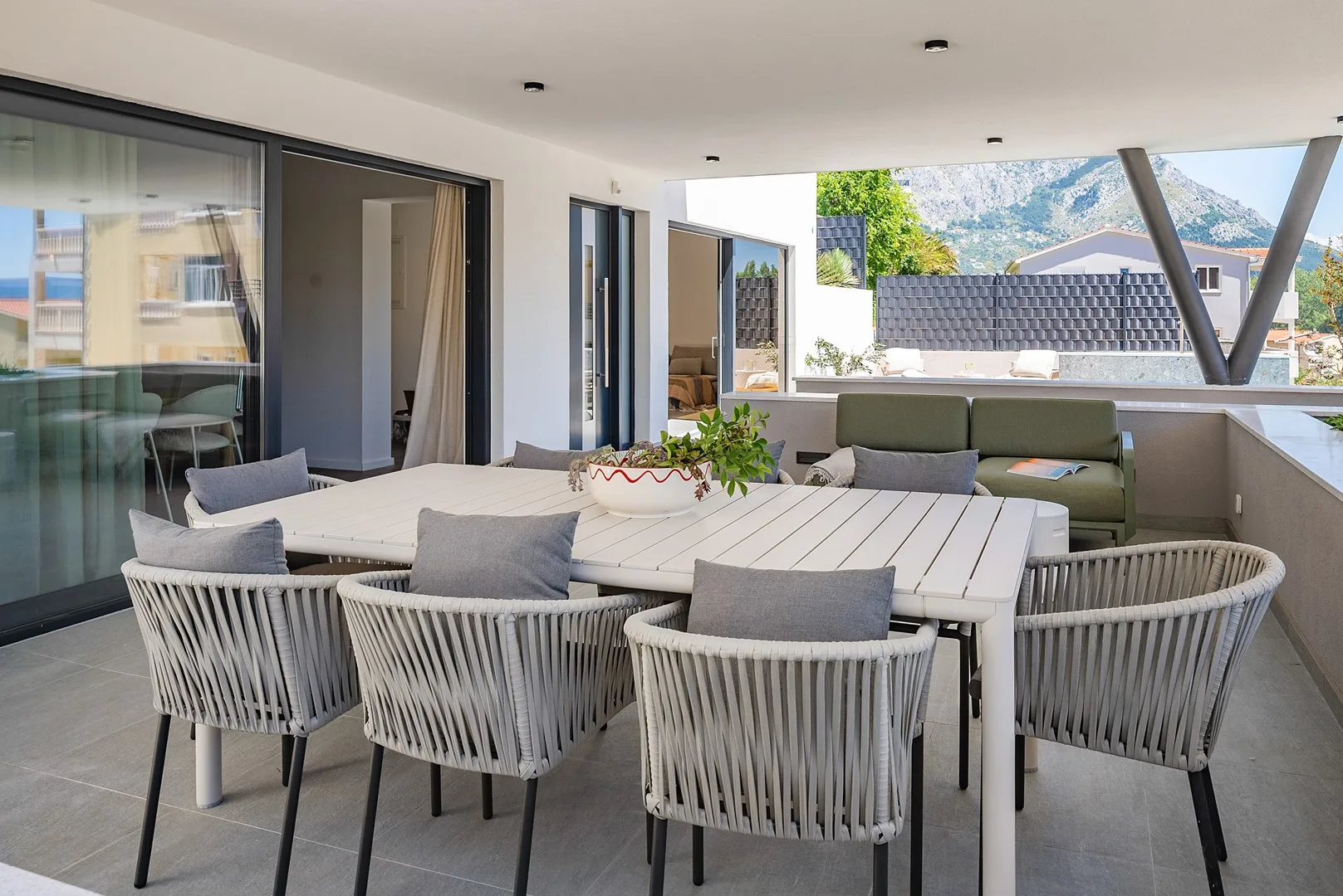 A covered outdoor dining area with a long table and surrounding seating.