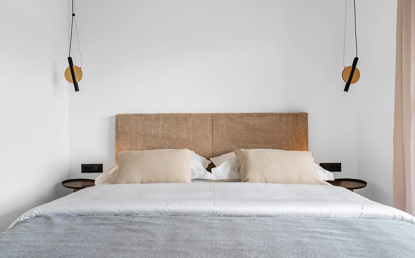 A bedroom with a neatly made bed and a padded headboard.