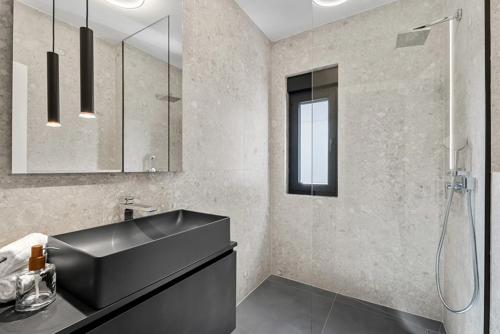A modern bathroom with a dark vanity and a shower.