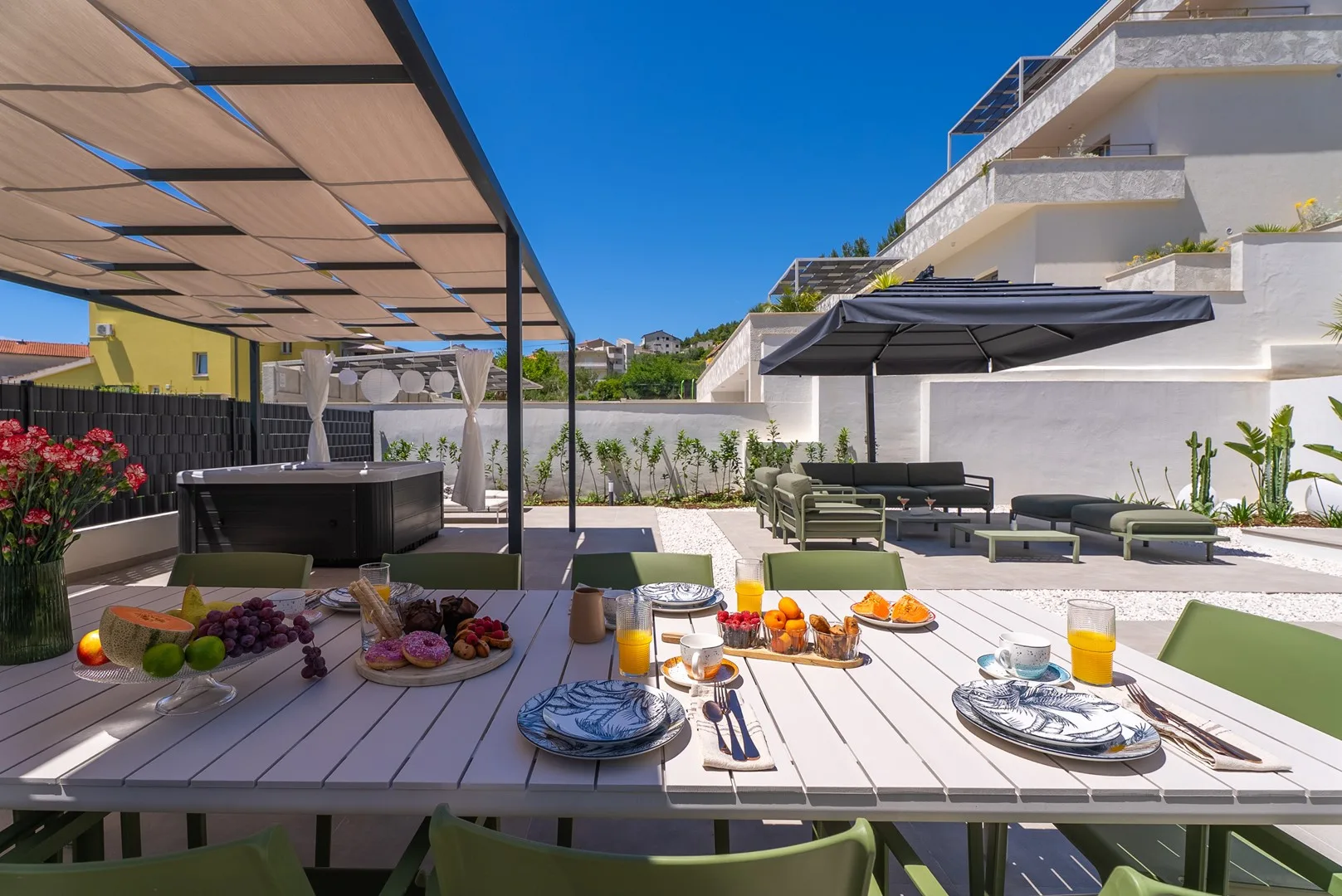 A sunny outdoor dining patio with a table set beneath a shade canopy.