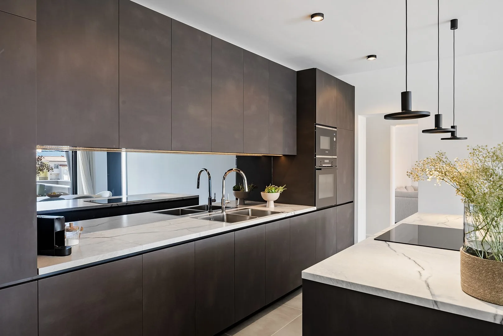 A modern kitchen with dark cabinets, a long counter, and an island.