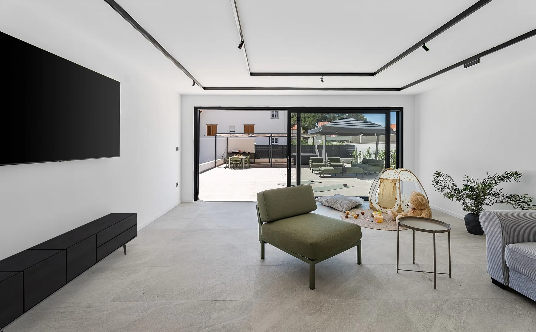 A bright living room opens onto a patio, with a lounge seat and television.