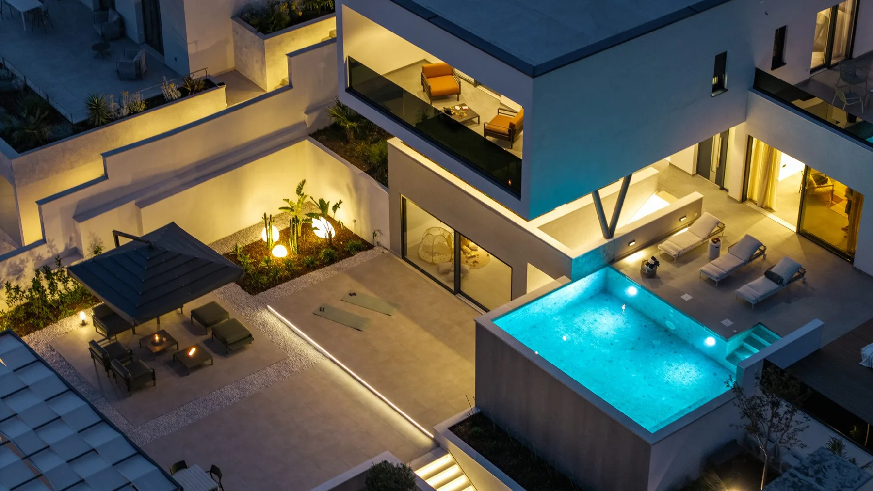 A modern house with a lit swimming pool and outdoor seating.