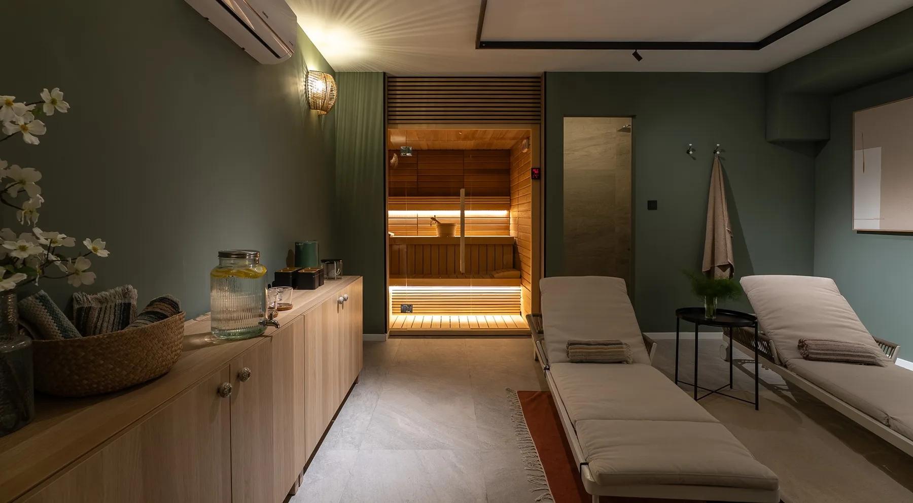 A spa room with two reclining loungers and a wooden sauna at the back.