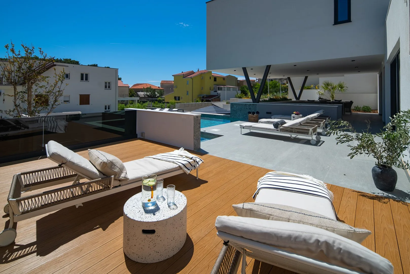 A modern outdoor terrace with lounge seating, a pool, and a wooden deck.