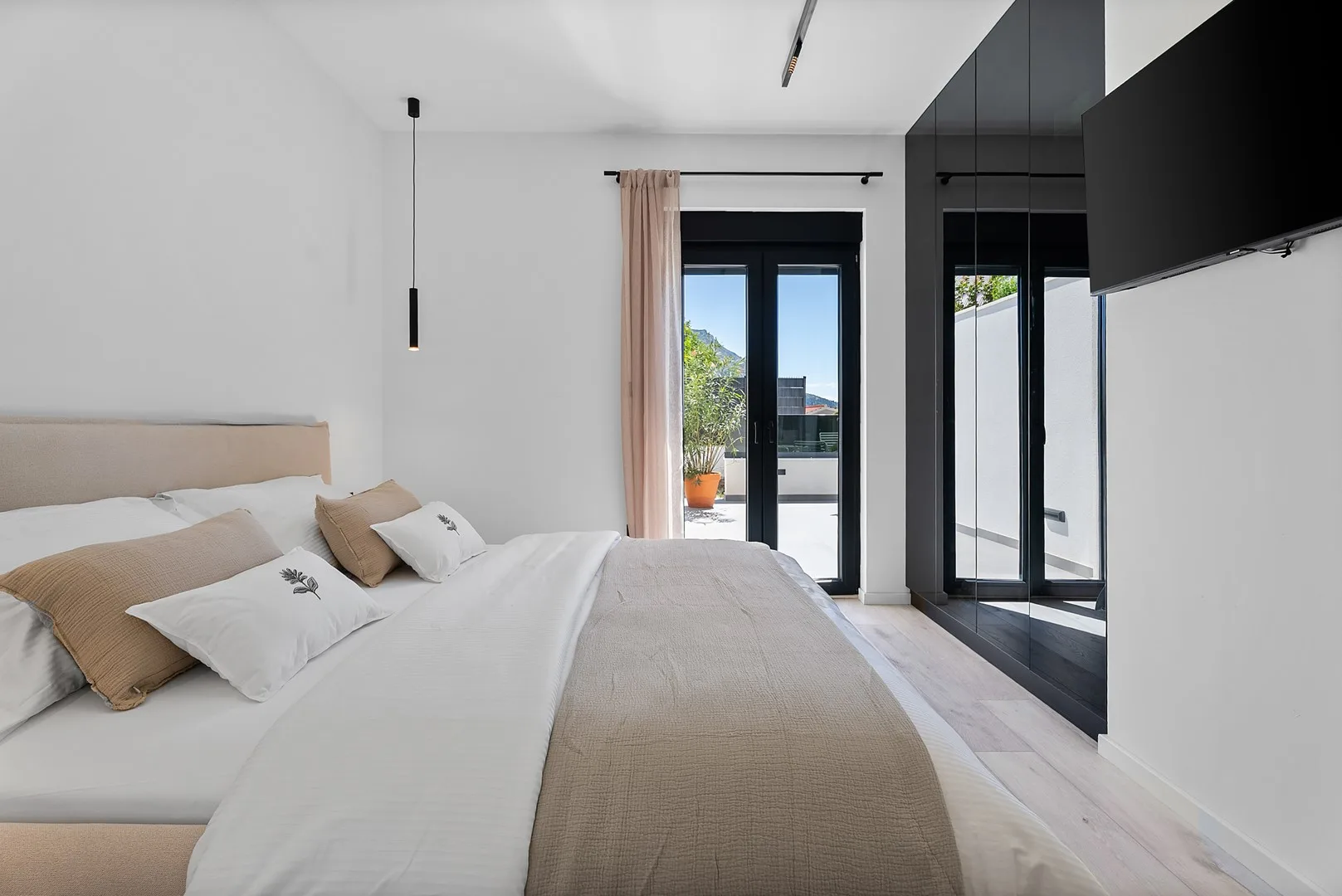 A bright bedroom with a bed and glass doors opening onto a balcony.